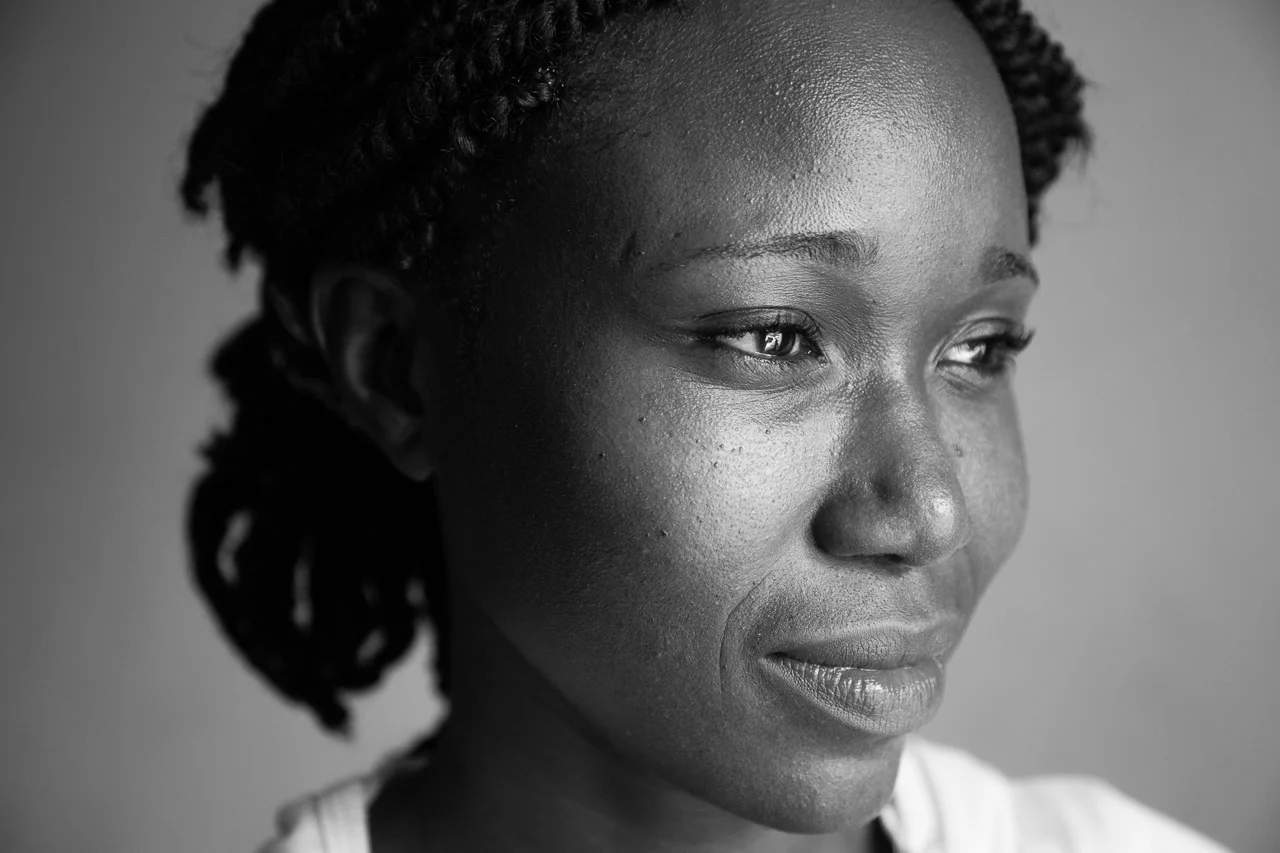 Close-up black-and-white portrait of a woman with natural hair, looking thoughtfully to the side.