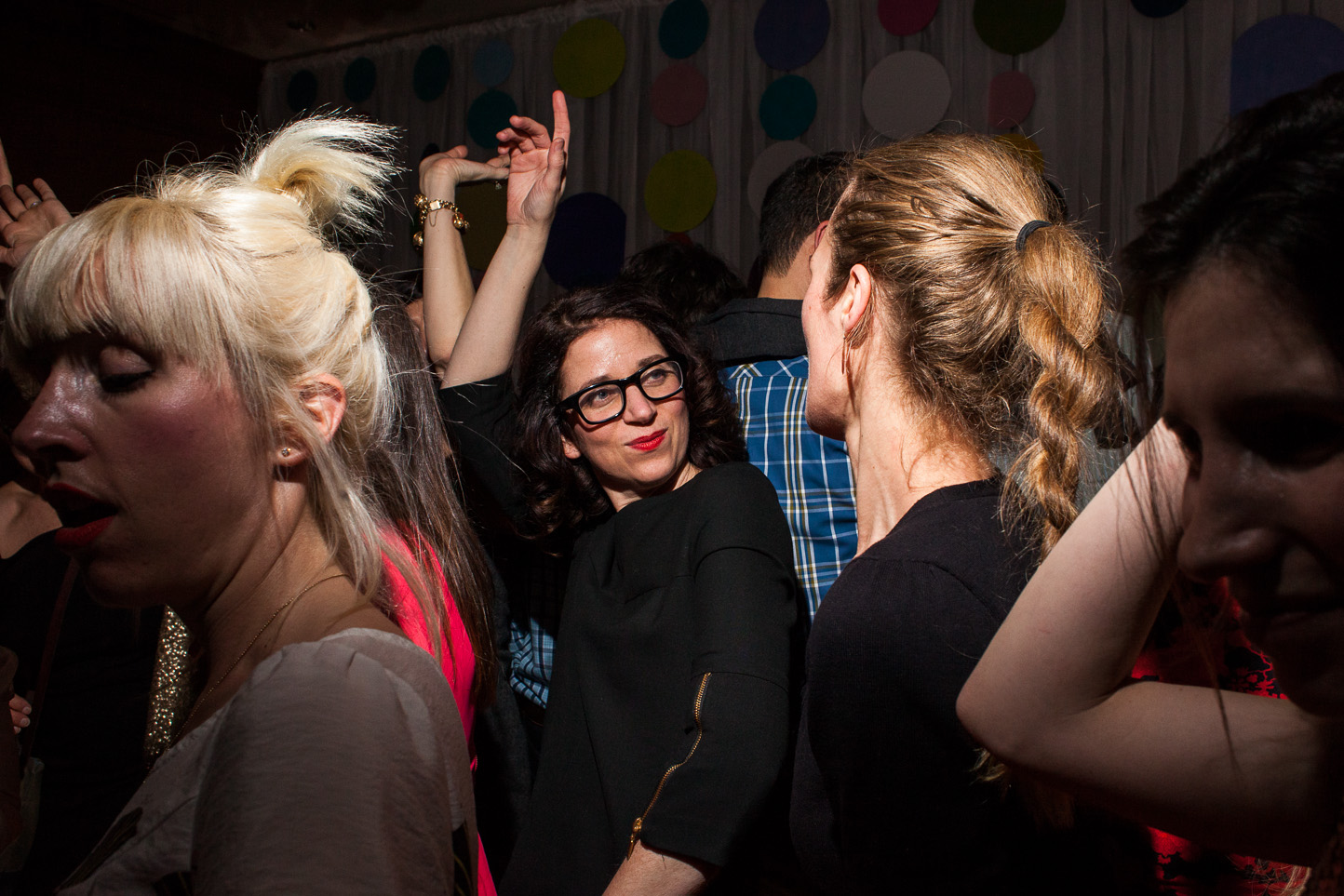 People dancing and socializing at a party with colorful balloons in the background.