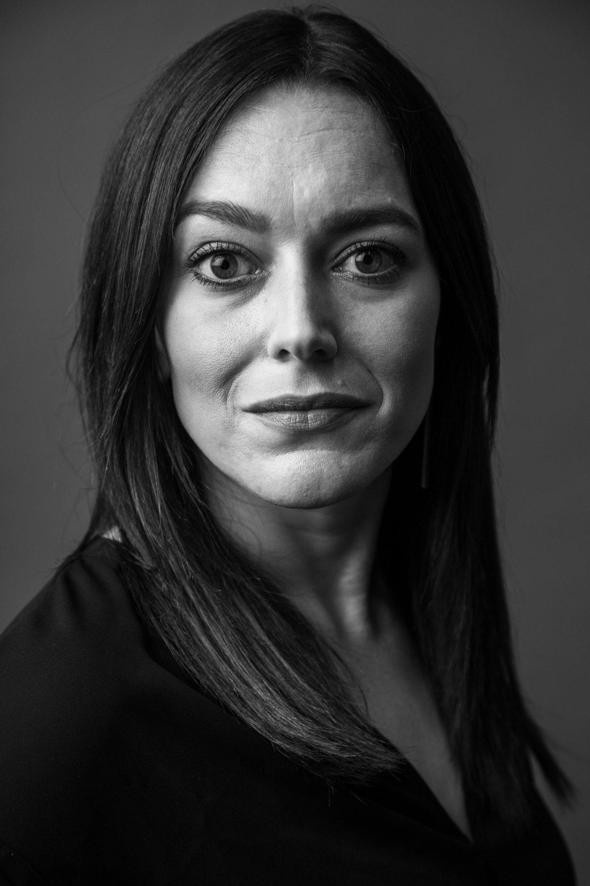 Black and white portrait of a woman with straight dark hair, looking directly at the camera with a neutral expression.