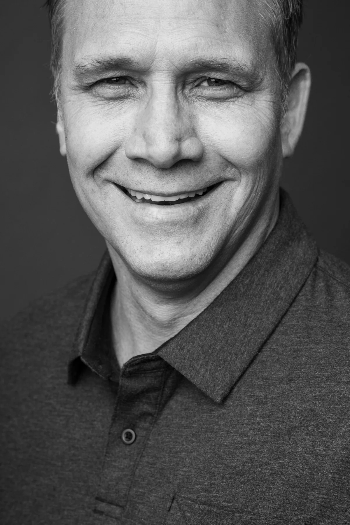 Black and white portrait of a smiling man in a collared shirt.