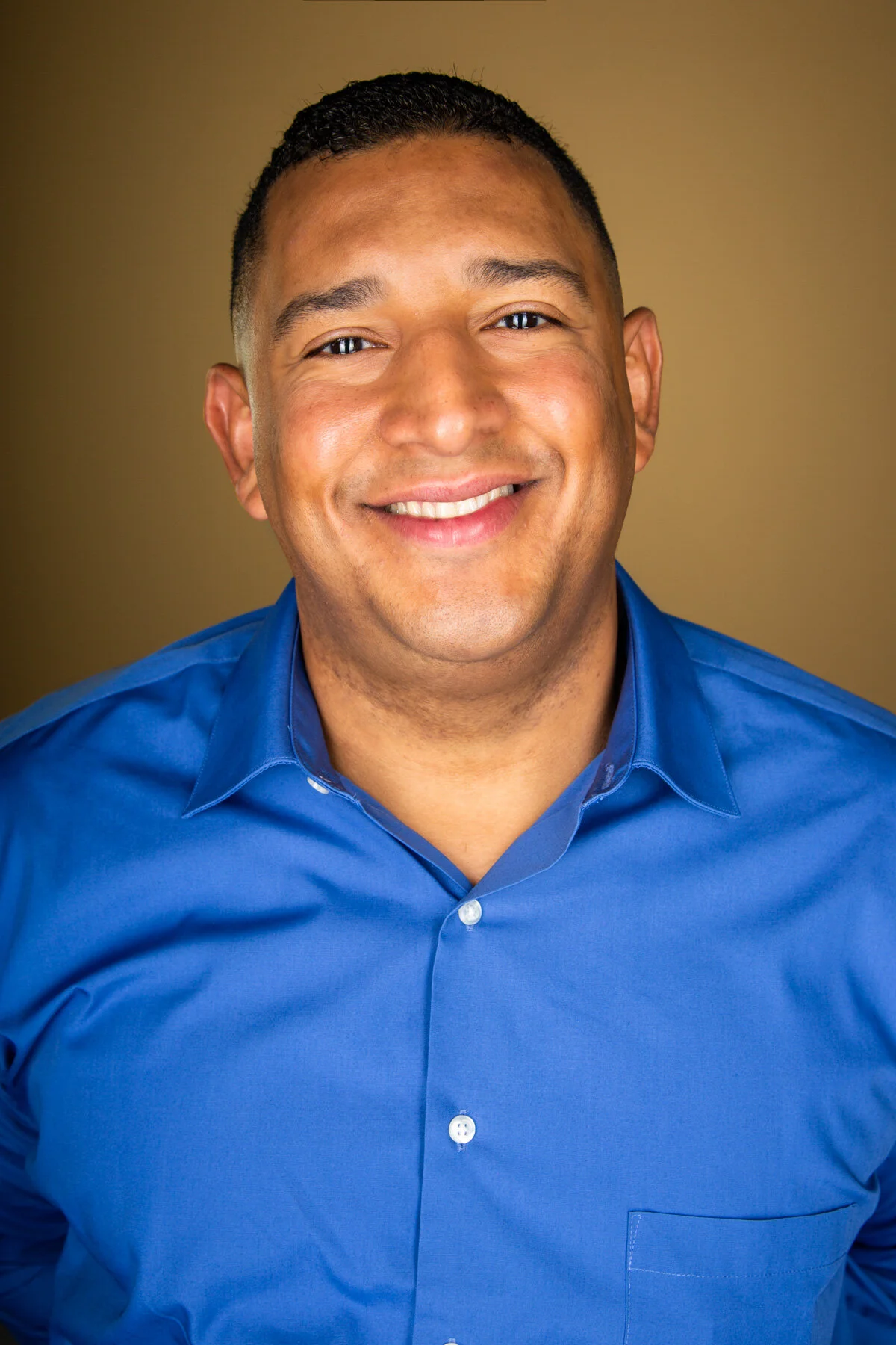 Headshot of a man wearing a blue shirt smiling at the camera.