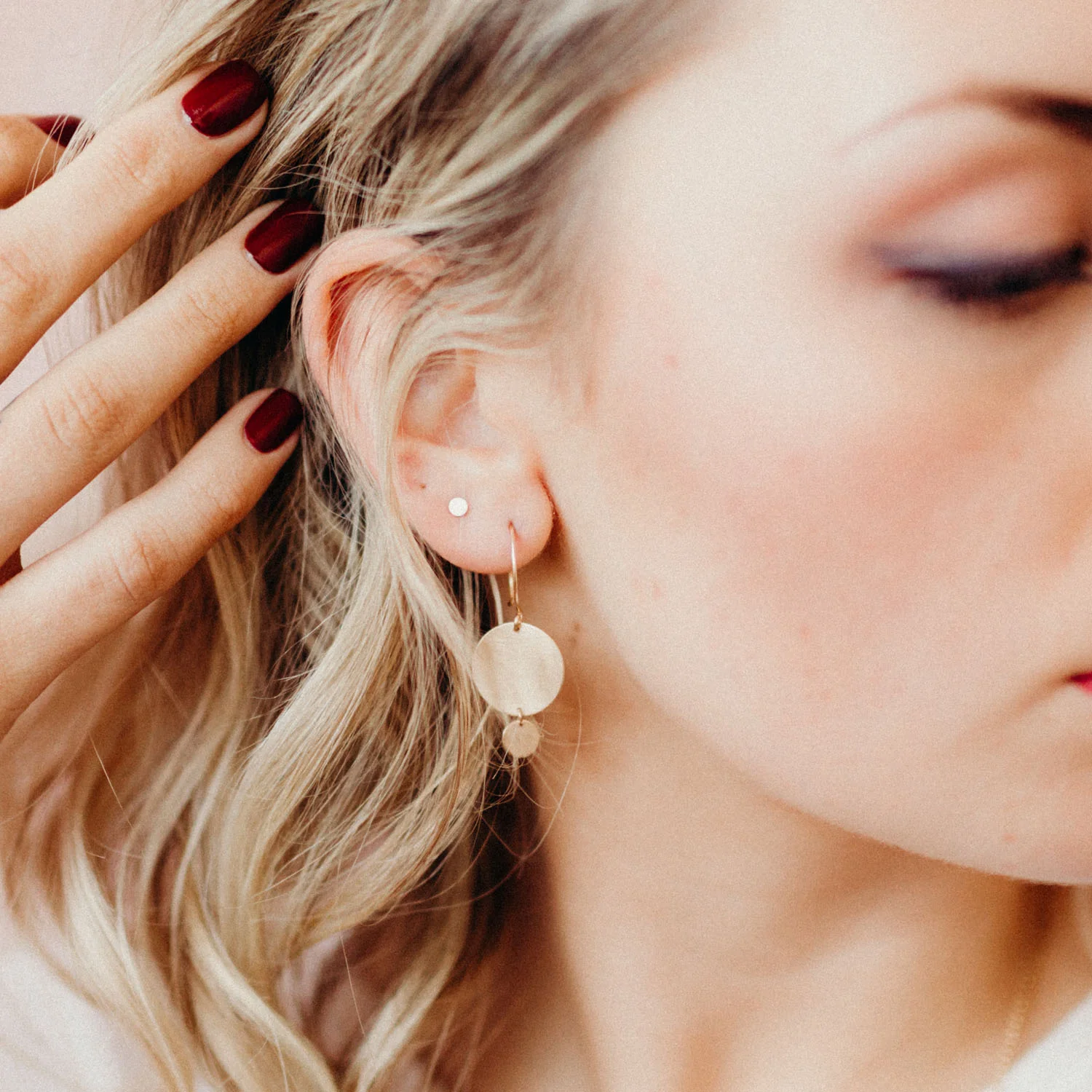 Metal discs swing and reflect light from handmade ear wires. These minimal and delicate earrings flash reflections of light right at the jaw line, creating a universally flattering accessory.