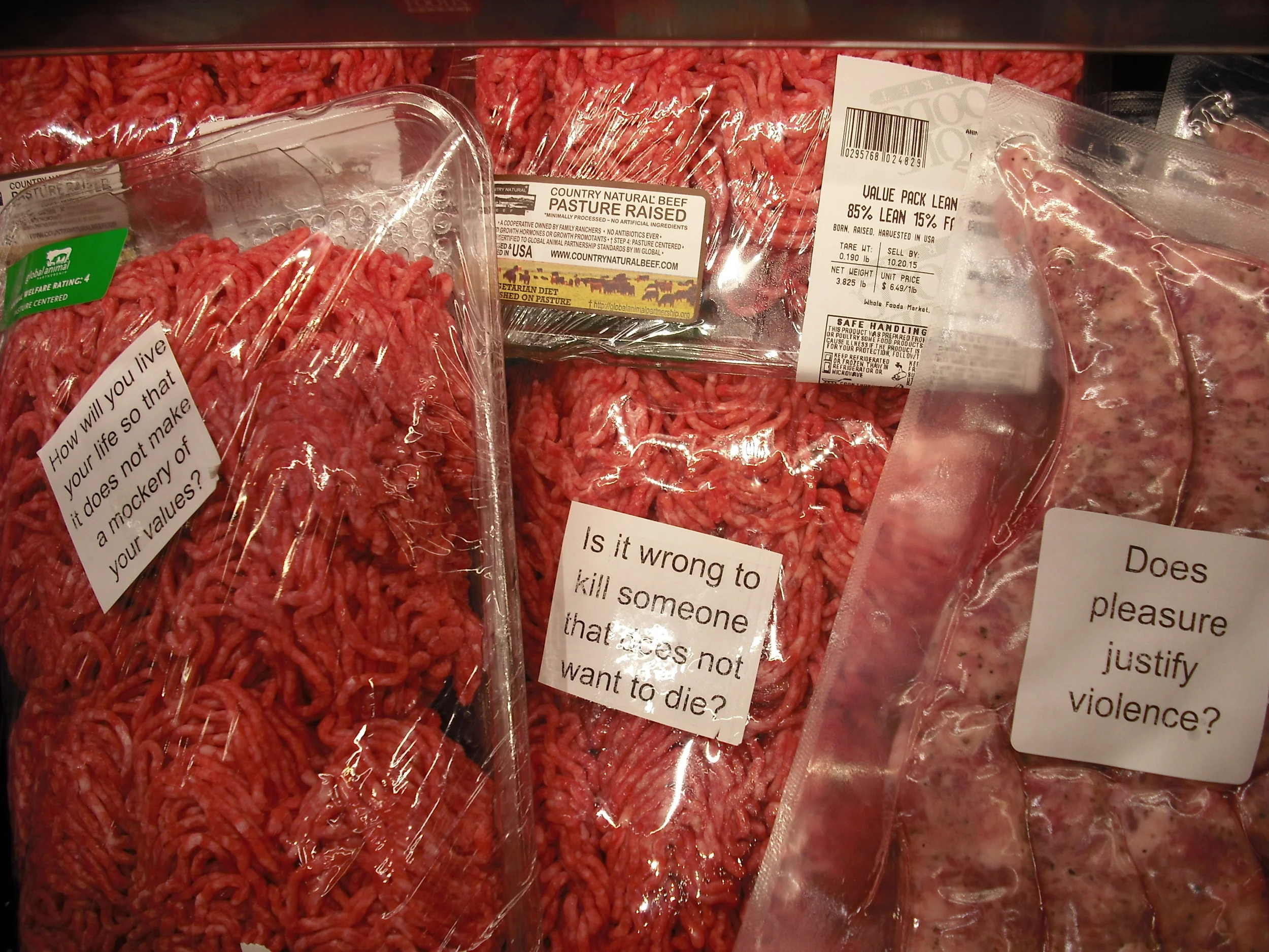 Packages containing animal flesh covered in stickers questioning the norms around eating animals' bodies.