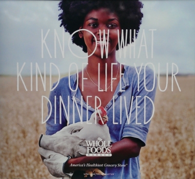 An ad from Whole Foods' "Values Matter" campaign. Here, a human is holding a chicken lovingly with the strange caption "Know what type of life your dinner lived."