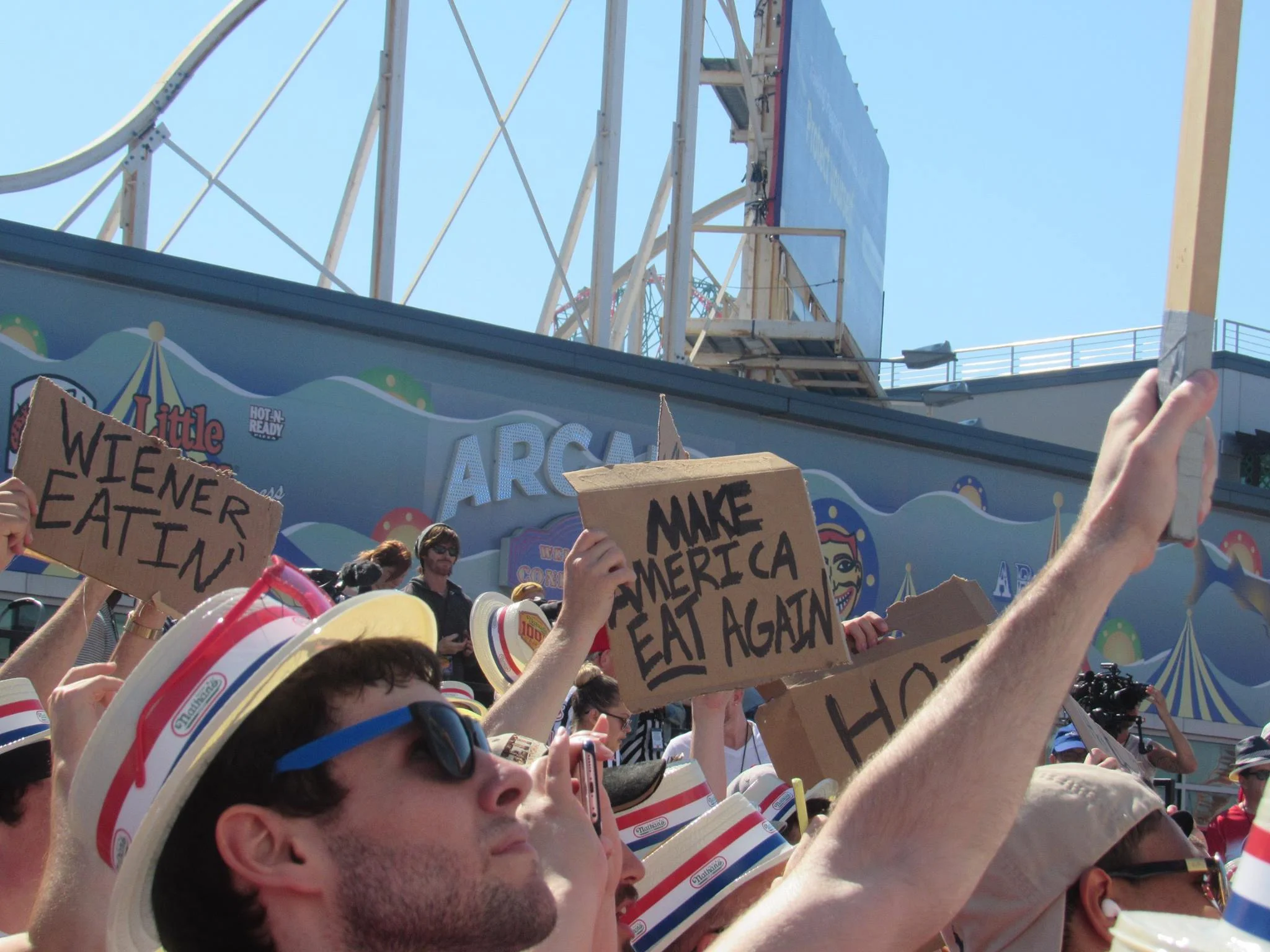 An event-goer holds a sign that says "MAKE AMERICA EAT AGAIN"