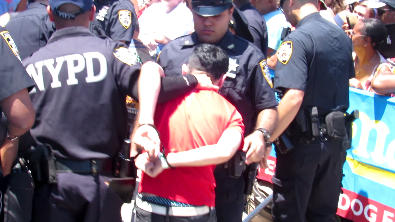 Several policemen aggressively haul off Jared, one of the activists, including a hand around the back of his neck