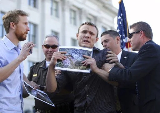 DxE’s Matt Johnson disrupts a Norbest turkey pardoning ceremony in Utah. He holds a photo of a nearly dead turkey found at a Norbest farm in 2017.