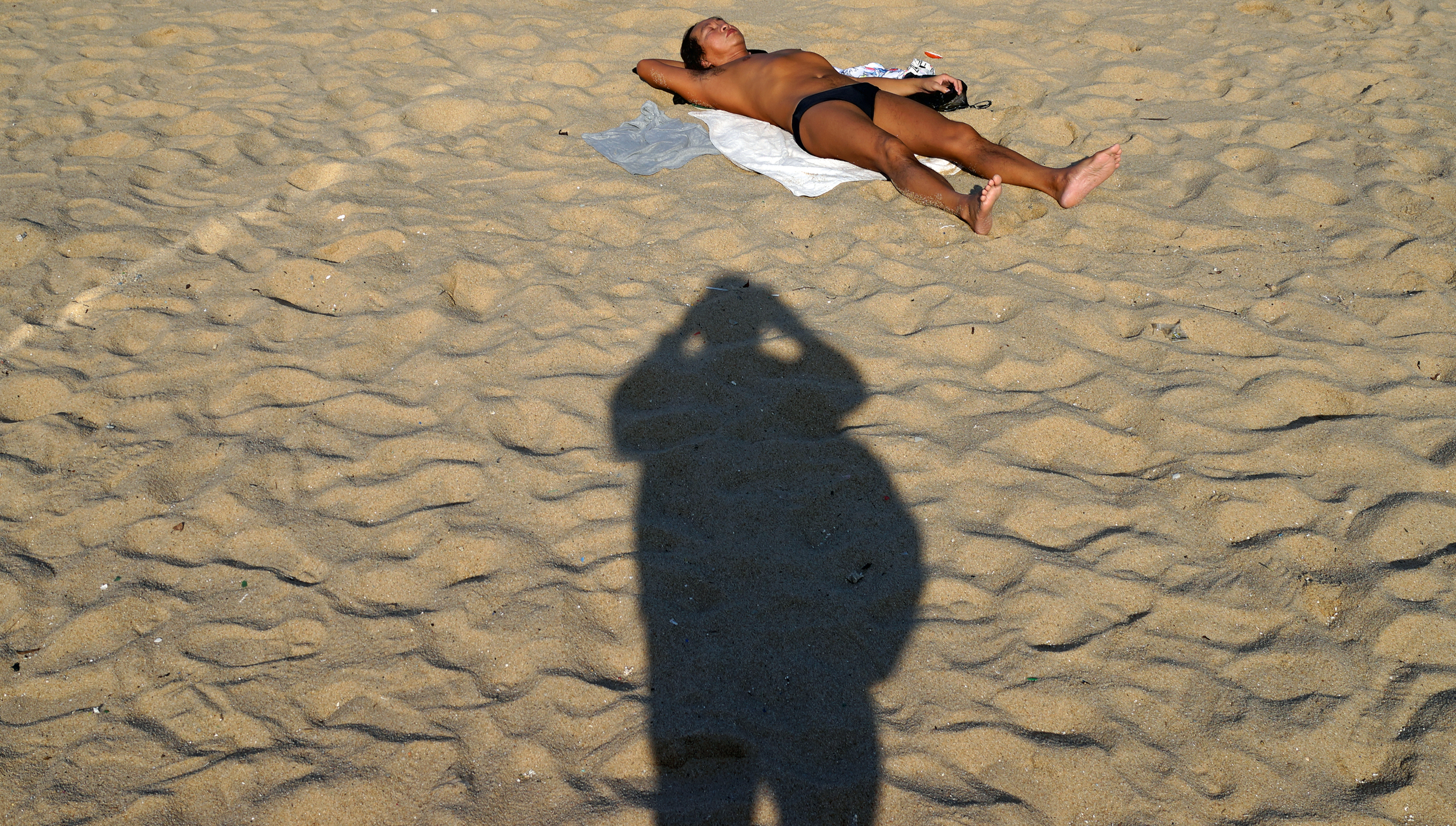 That's my shadow actually and it is a bag that makes look like I am 400lbs!! the chap catching the rays is lying on Cheung Chau Beach near the Miami Resort.