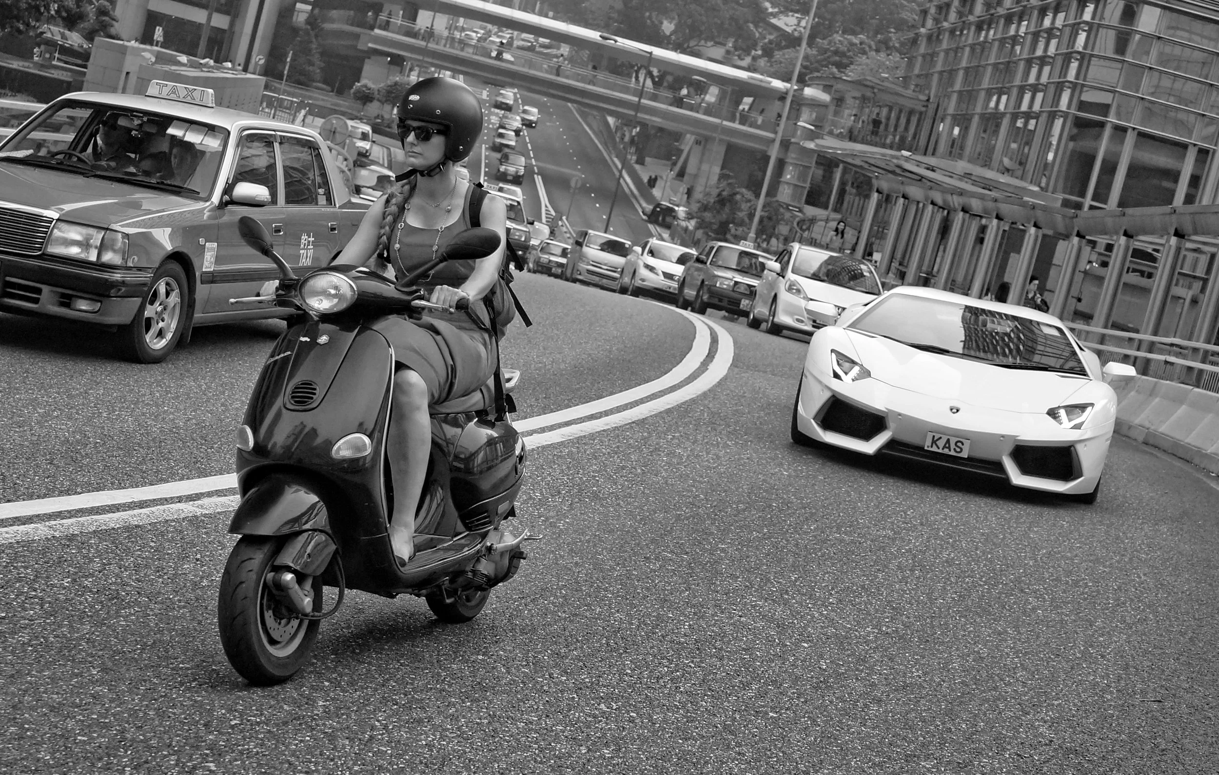 Lady on a scooter vs a chap in a Lamborghini, Garden Road, Hong Kong.jpg