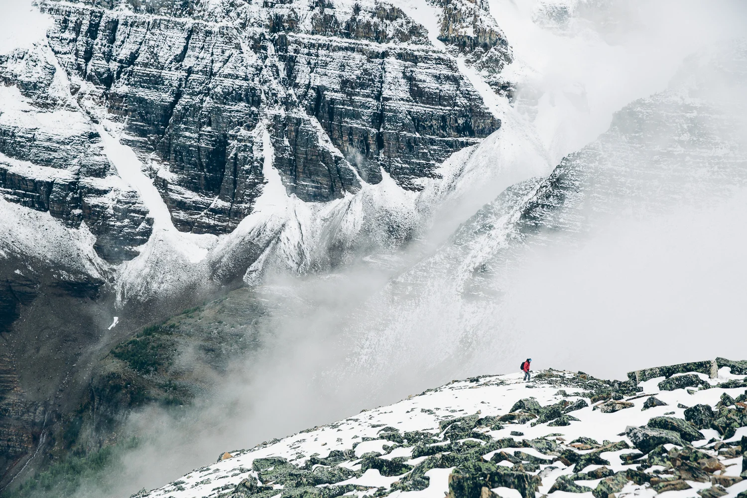 Hiker exploring the misty summit of Mount Fairview near Lake Louise, Alberta.