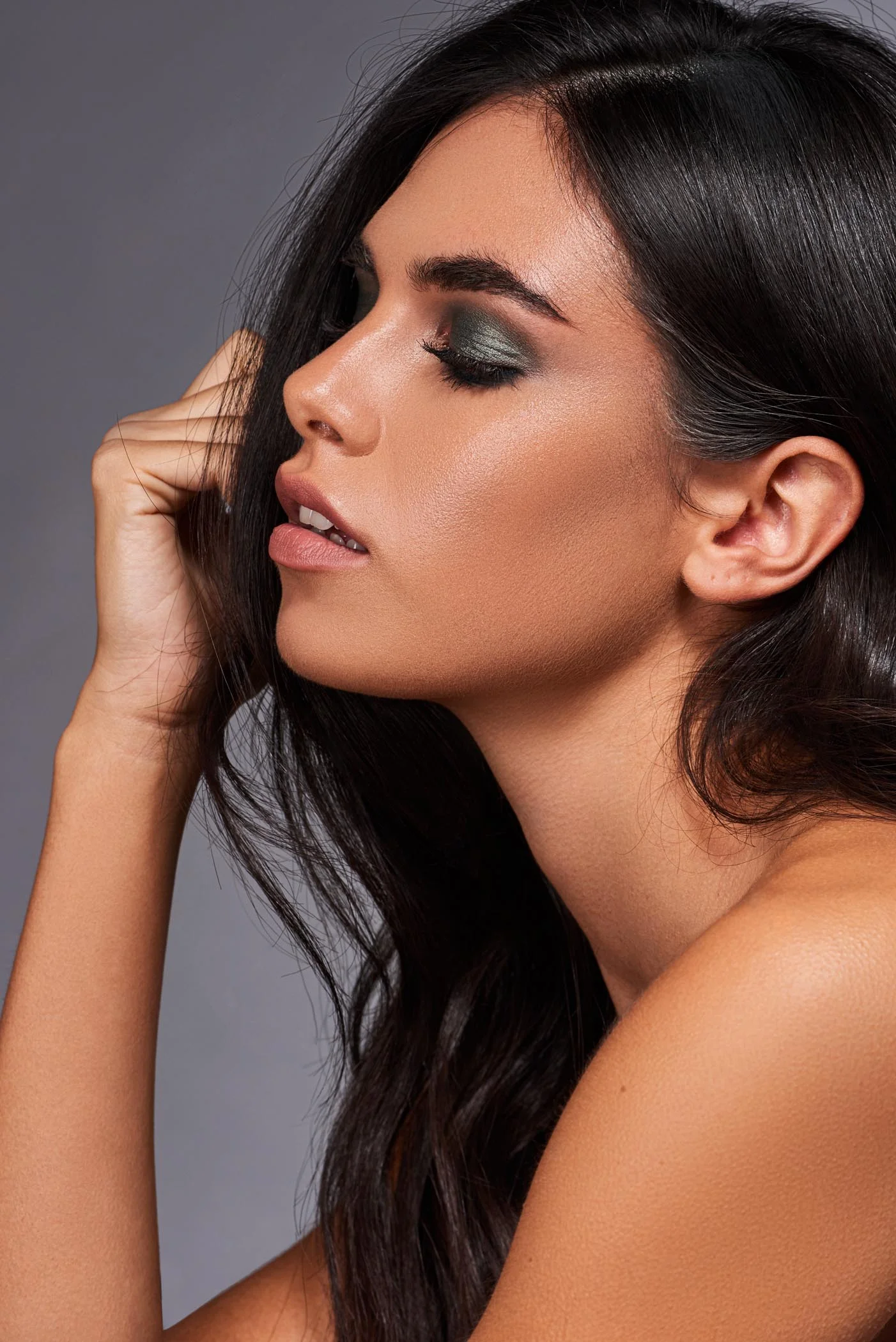 Beauty model with long black hair, dark green eyeshadow and glossy skin