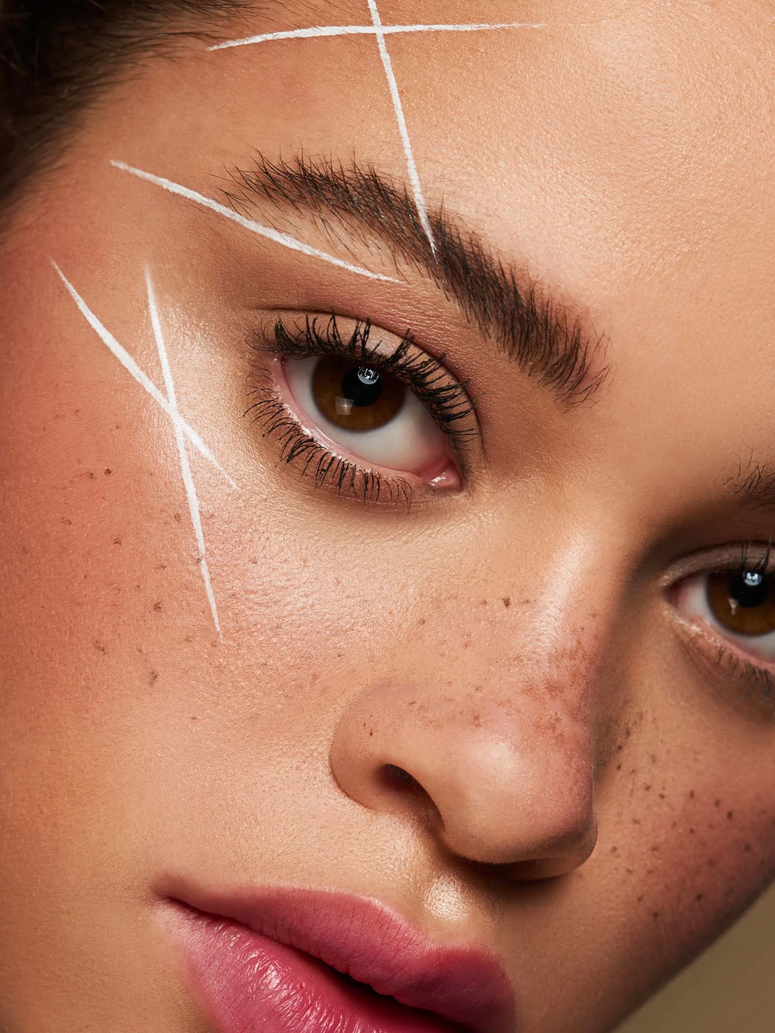 close up beauty shoot featuring mixed race model with faux freckles and creative white face eyeliner