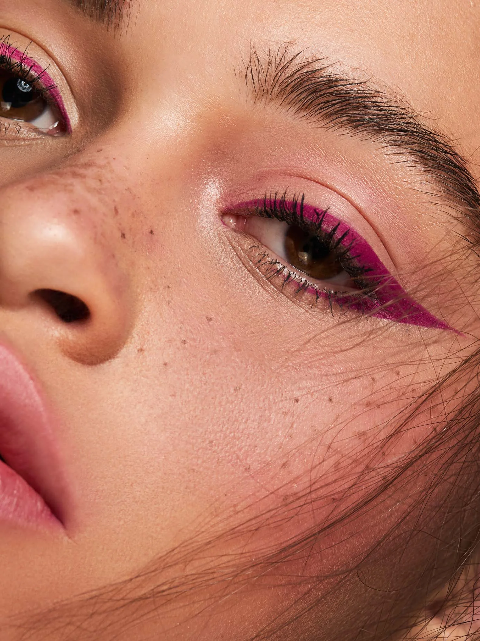 close up macro beauty shoot featuring mixed race beauty model with faux freckles and pink eyeliner