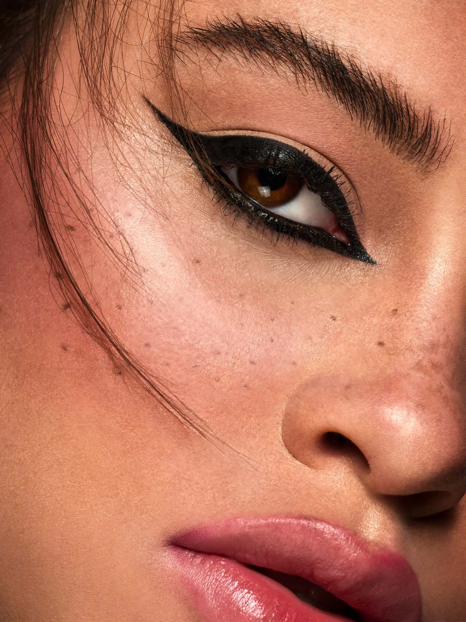 close up macro beauty shoot featuring mixed race beauty model with faux freckles and black eyeliner