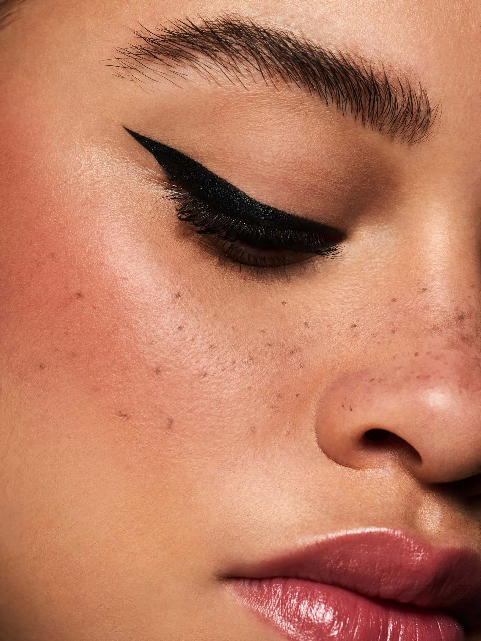 close up macro beauty shoot featuring mixed race beauty model with faux freckles and black eyeliner