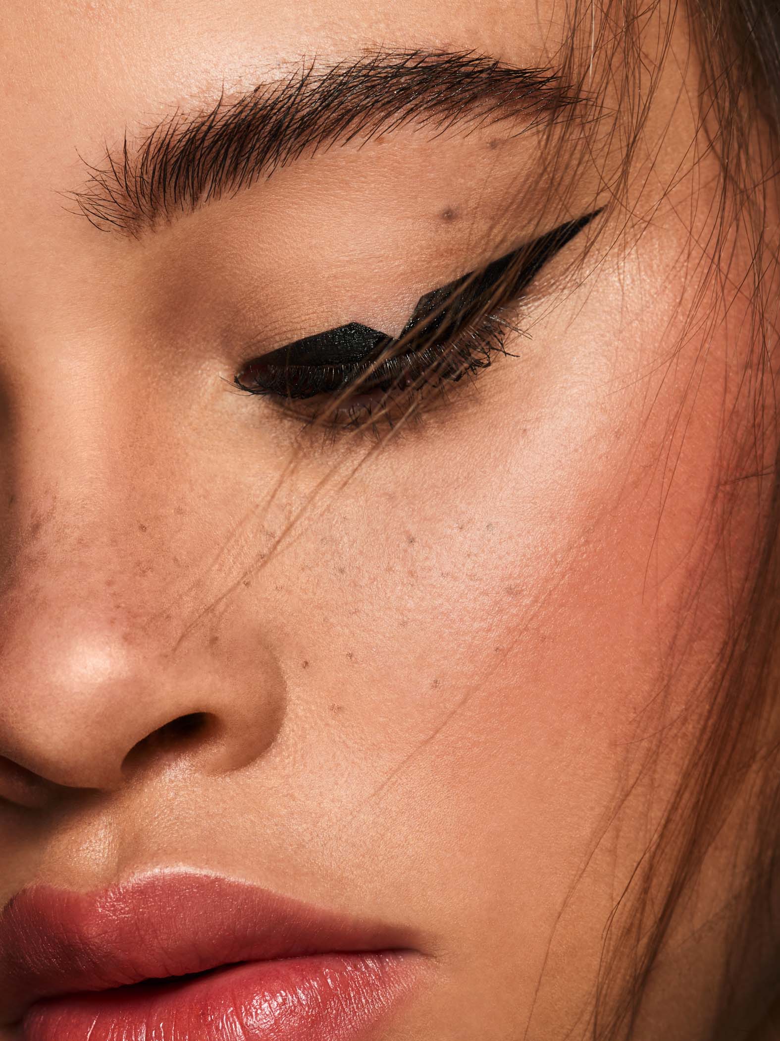 close up beauty shoot featuring mixed race model with faux freckles and creative black eyeliner