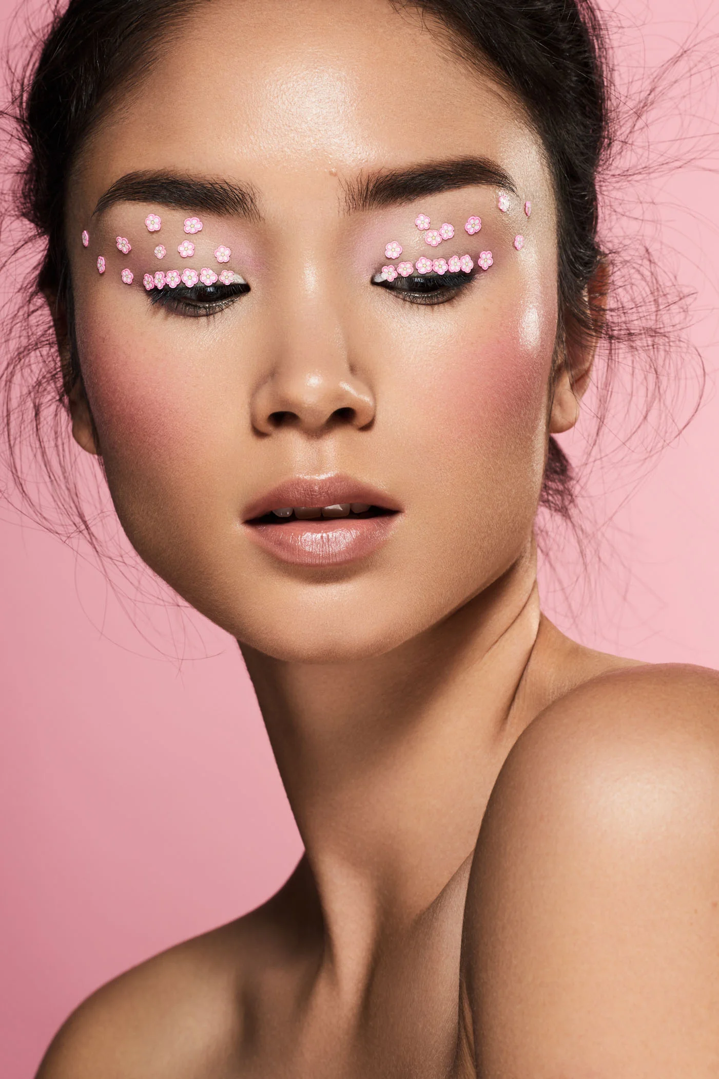 Asian beauty model with flower face stickers in front of a pink studio backdrop