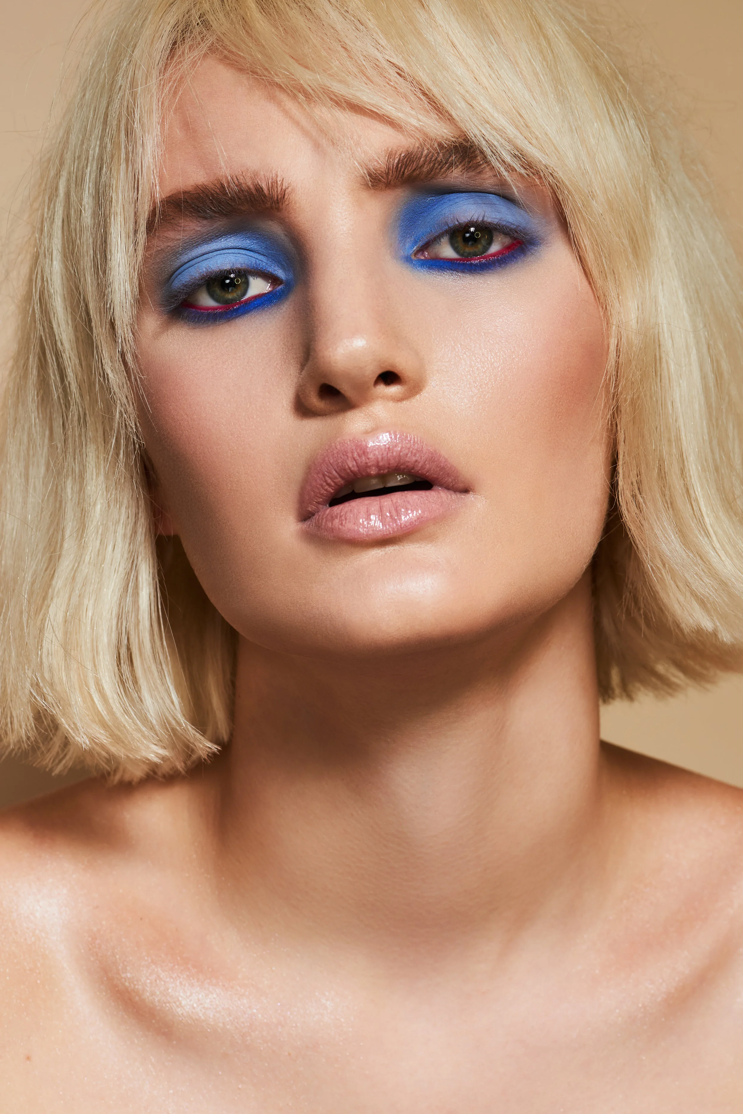 beauty model with blonde hair and blue coloured eyeshadow makeup during studio shoot 