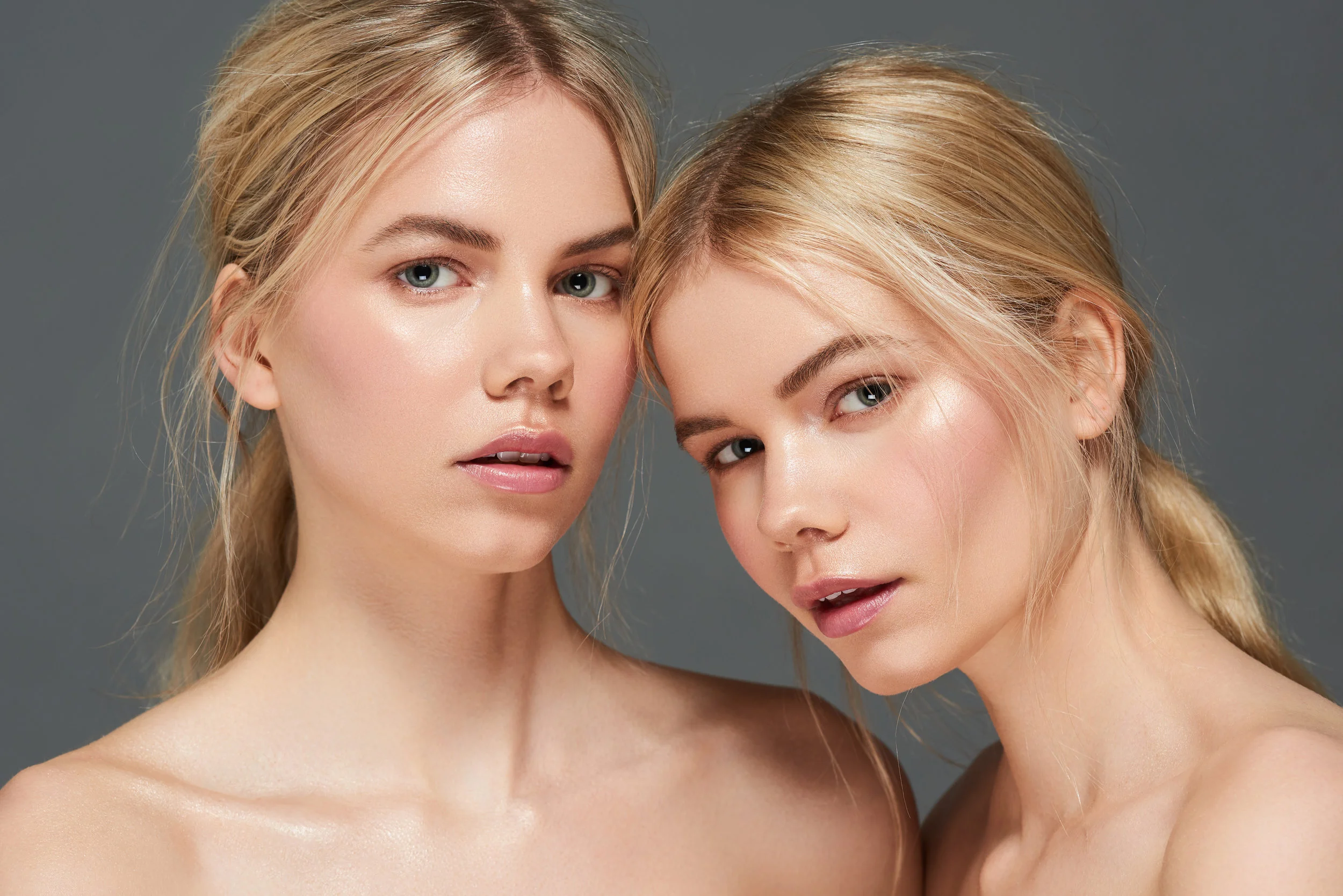 blonde female twins modelling for a skincare shoot with glossy flawless skin