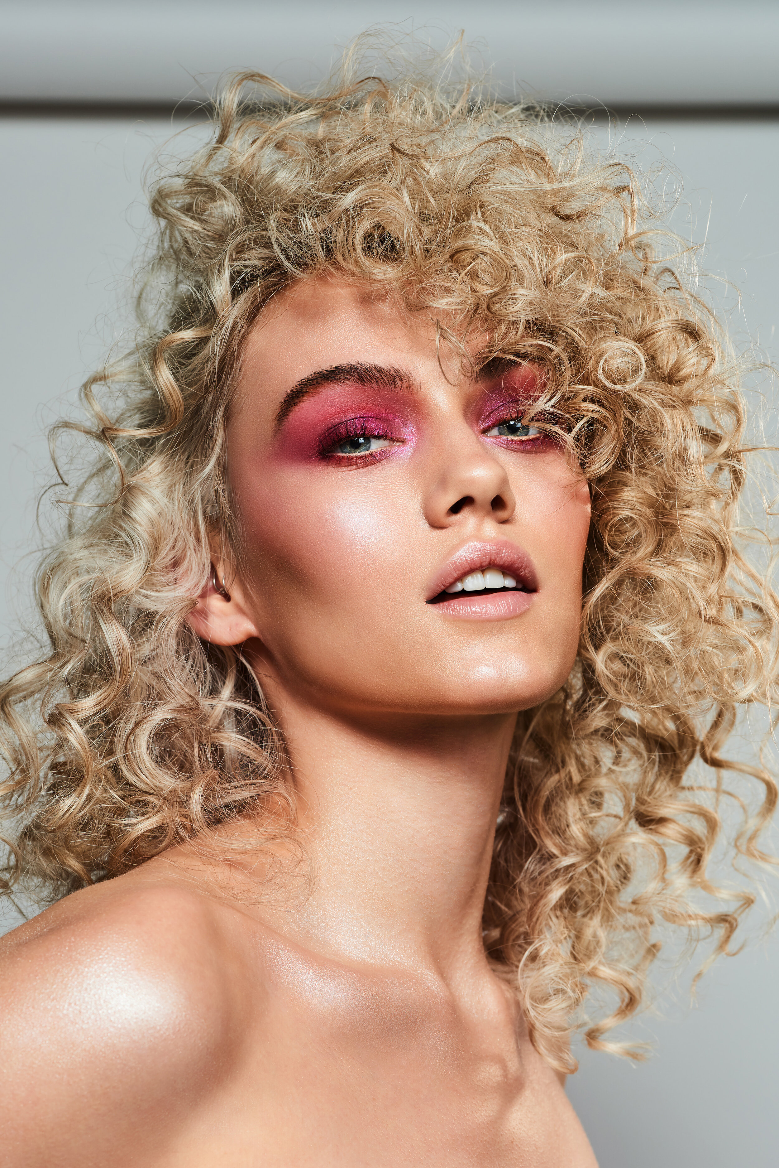 Blonde beauty model with big permed hair and pink eyeshadow makeup