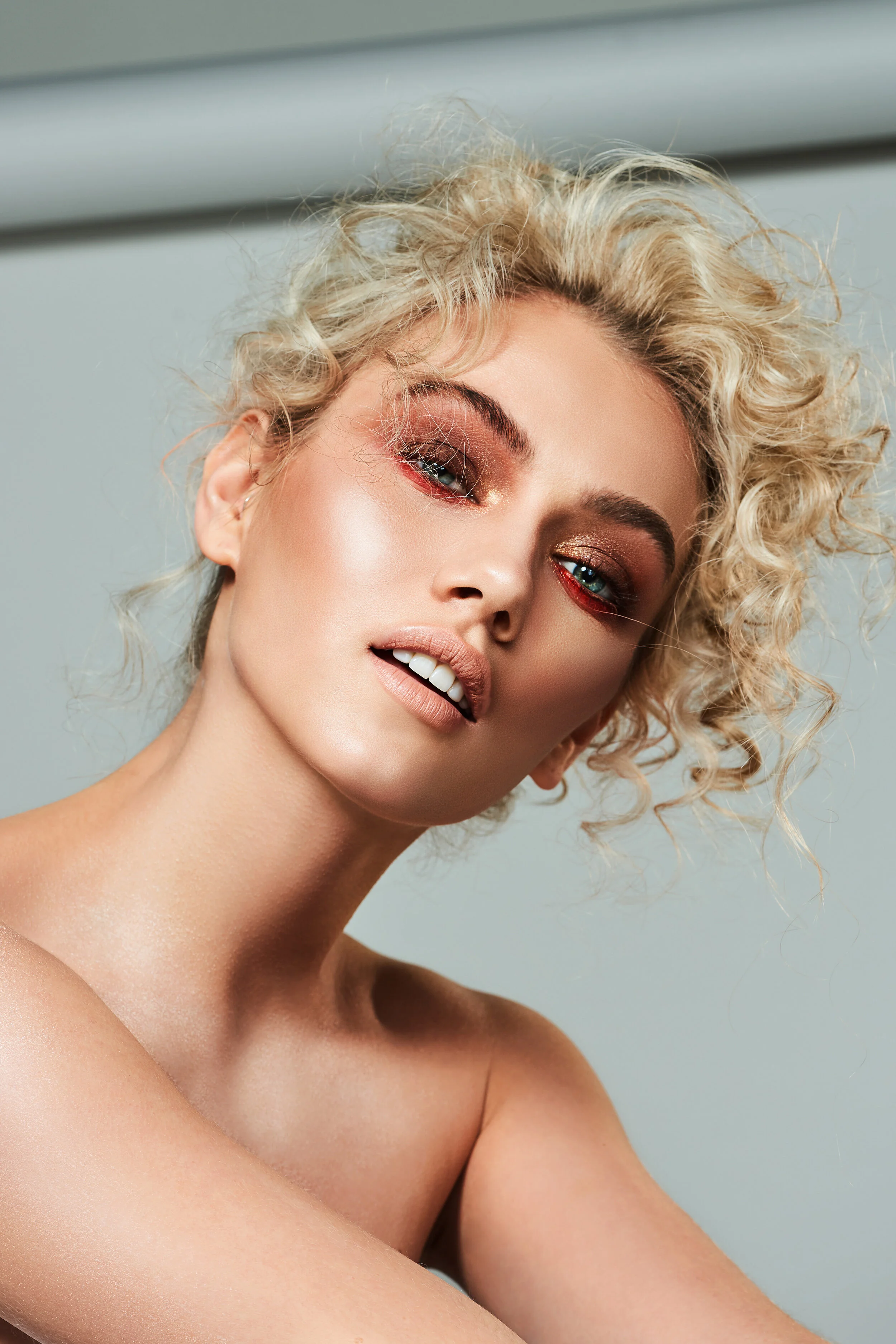 Blonde beauty model with permed hair and shimmer eyeshadow makeup