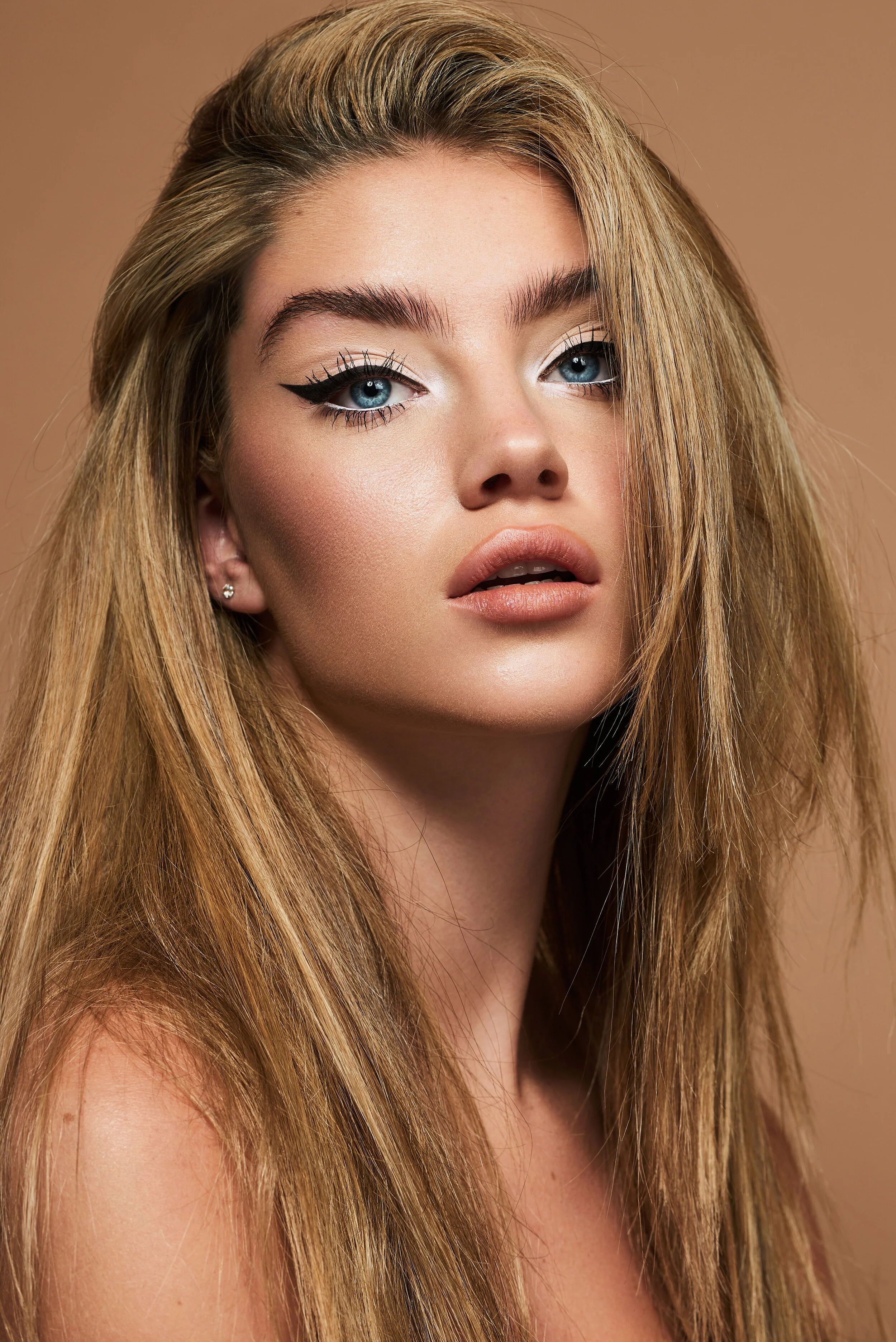 Female beauty model with dark blonde hair, black eyeliner and flawless skin
