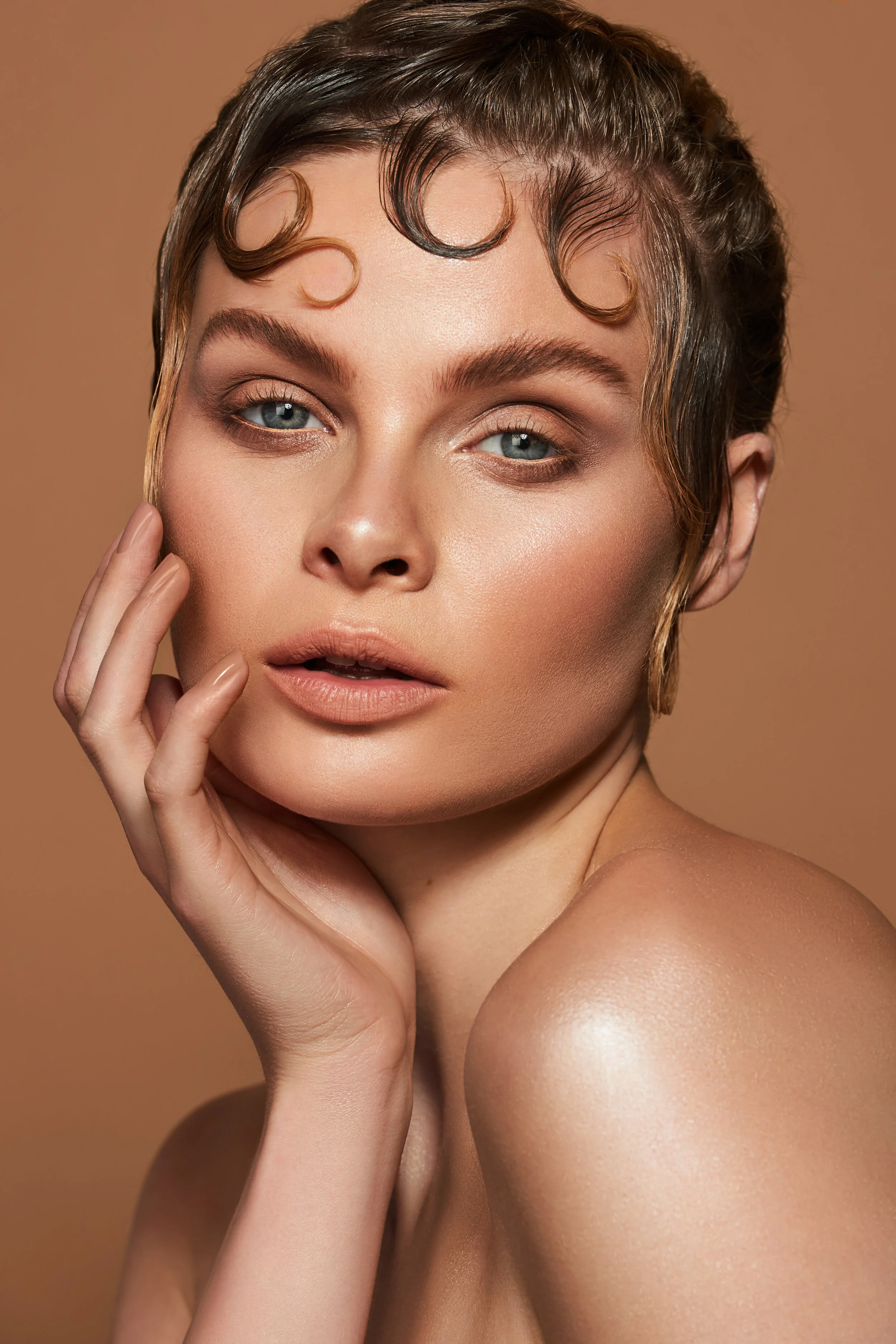 1920s kiss curls hair shoot with creative face gems on models face in front of beige background