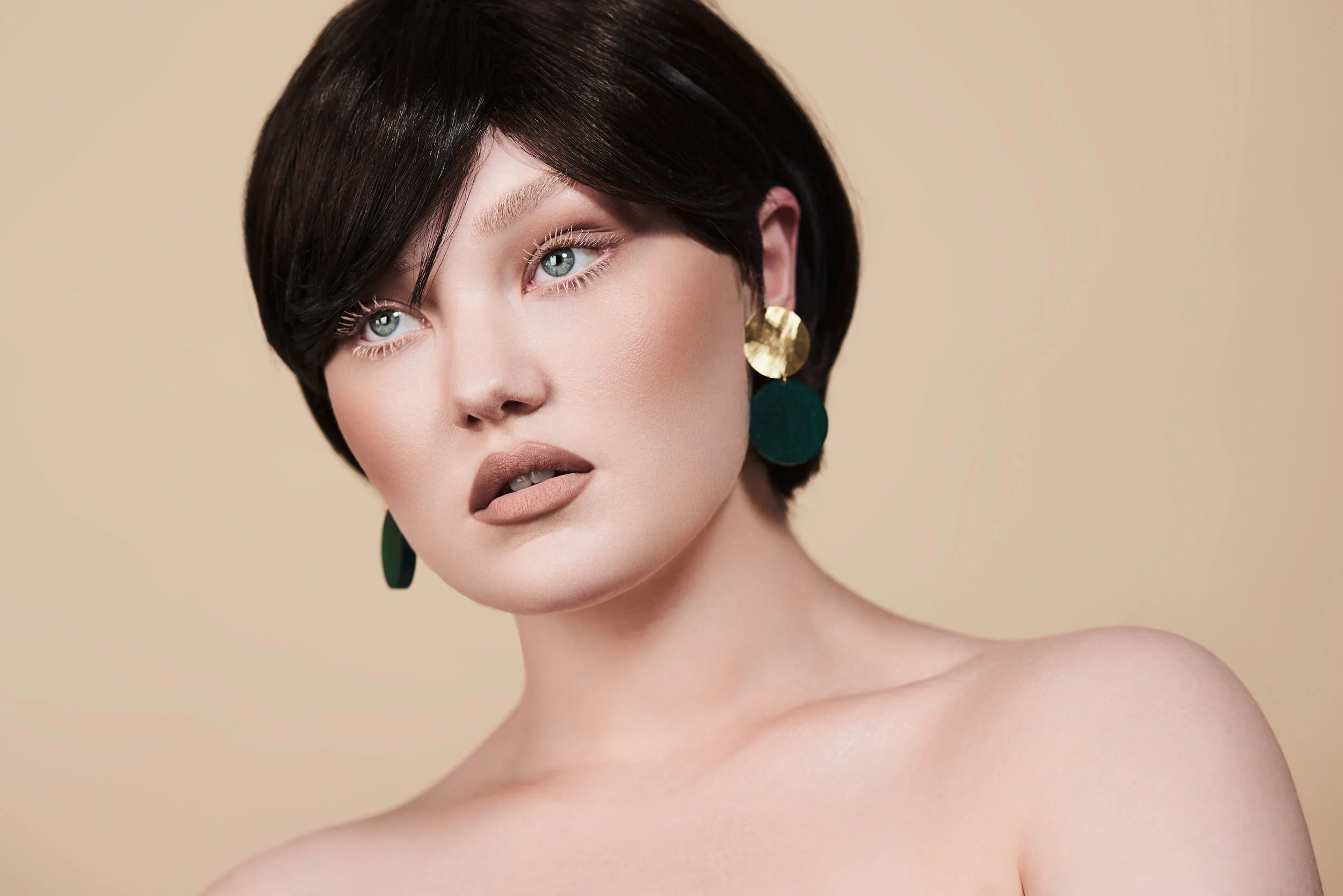 beauty model with pale skin and white eyelashes in front of cream backdrop wearing Bybri Jewellery