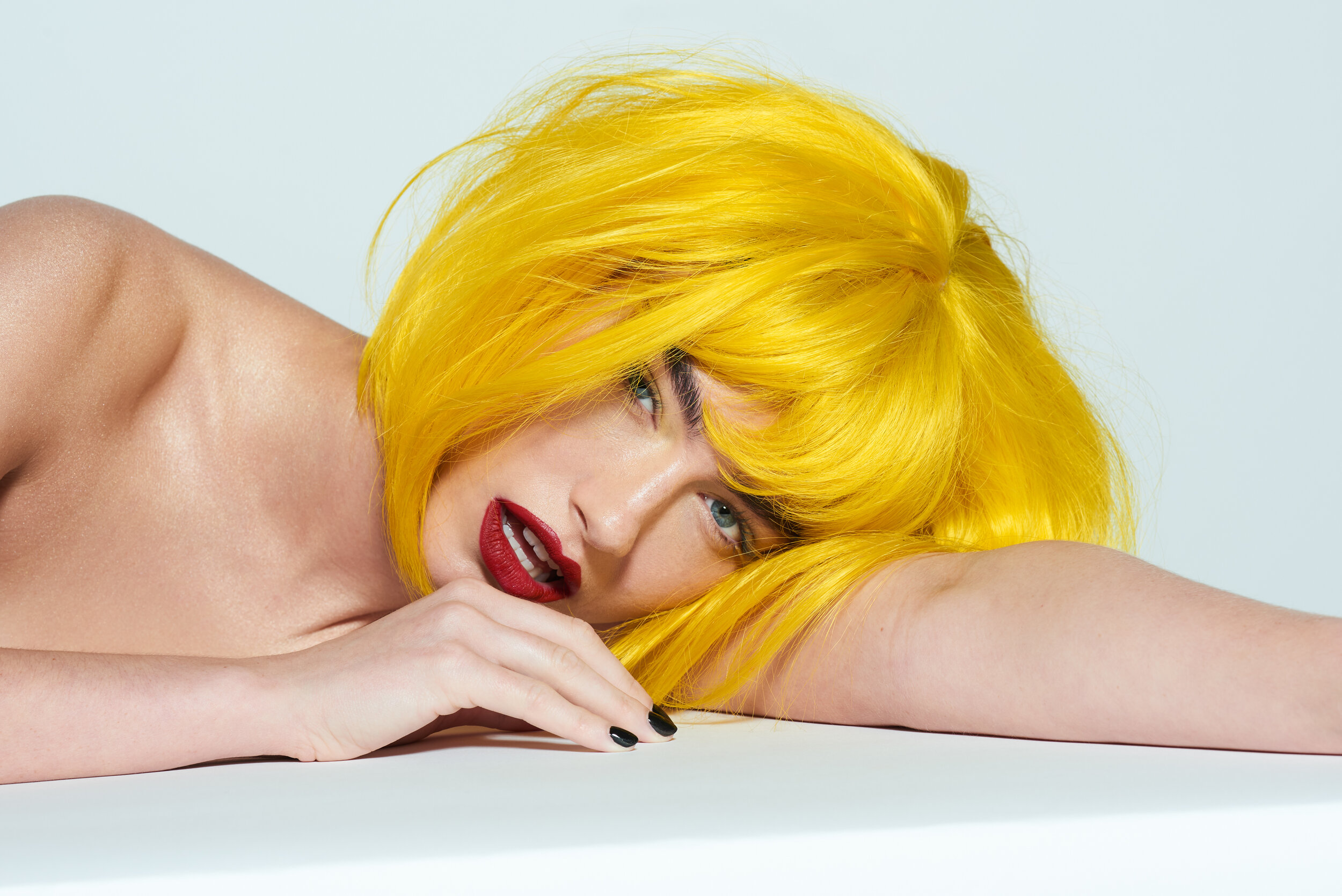 Female beauty model wearing a yellow wig for LGBT Hair shoot on white backdrop