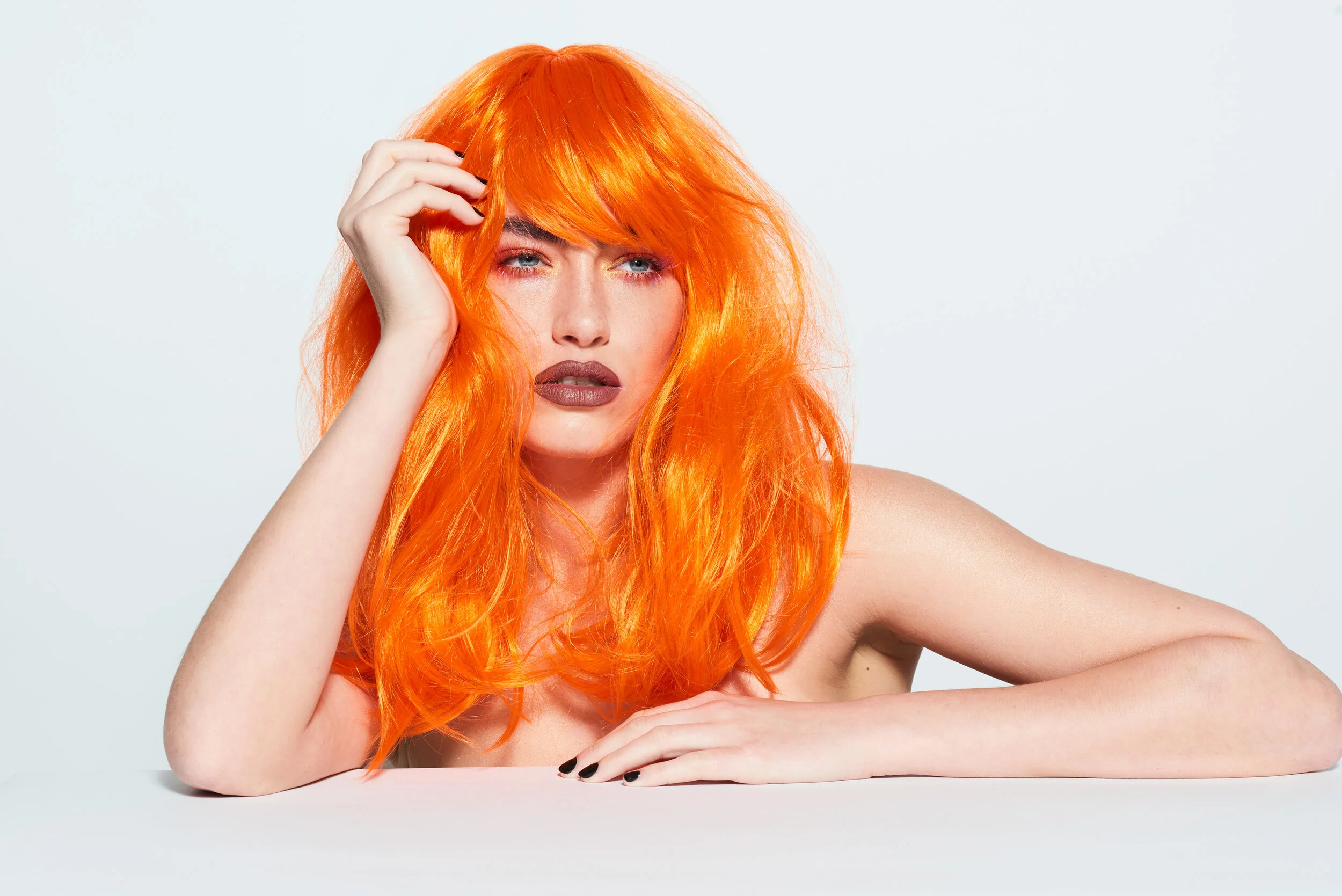 Female model wearing a orange wig with dark red lipstick for LGBT beauty studio shoot 