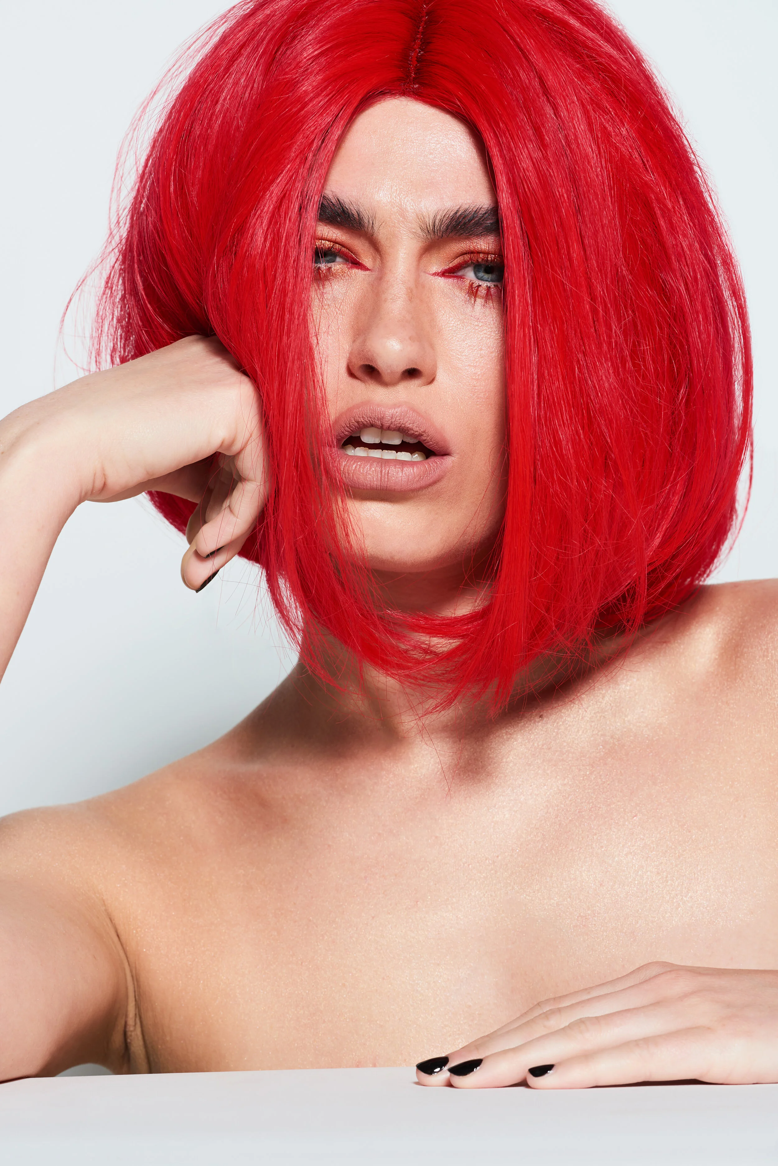 Female beauty model wearing a red wig for LGBT Hair shoot on white backdrop