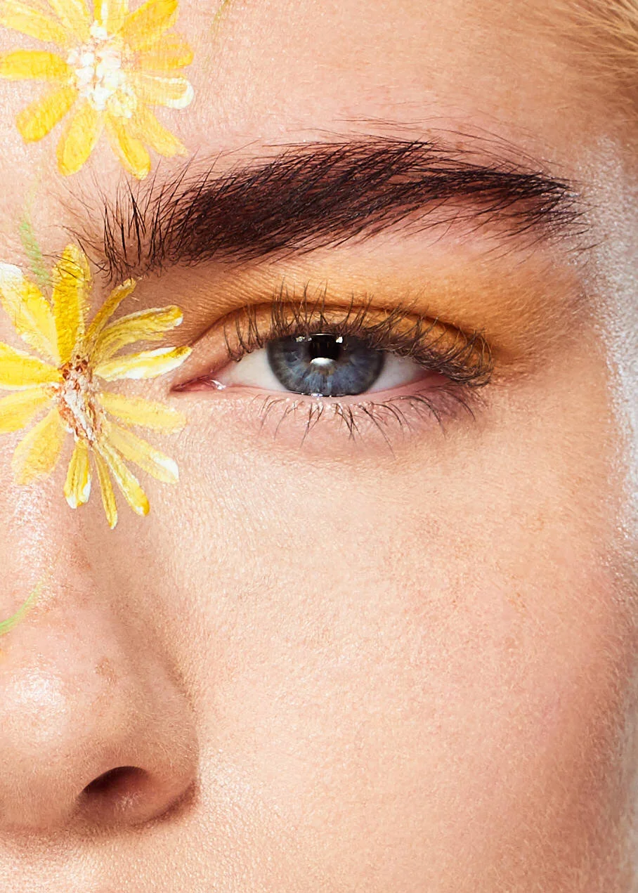 close up macro beauty shot of female model with yellow flower face paint art
