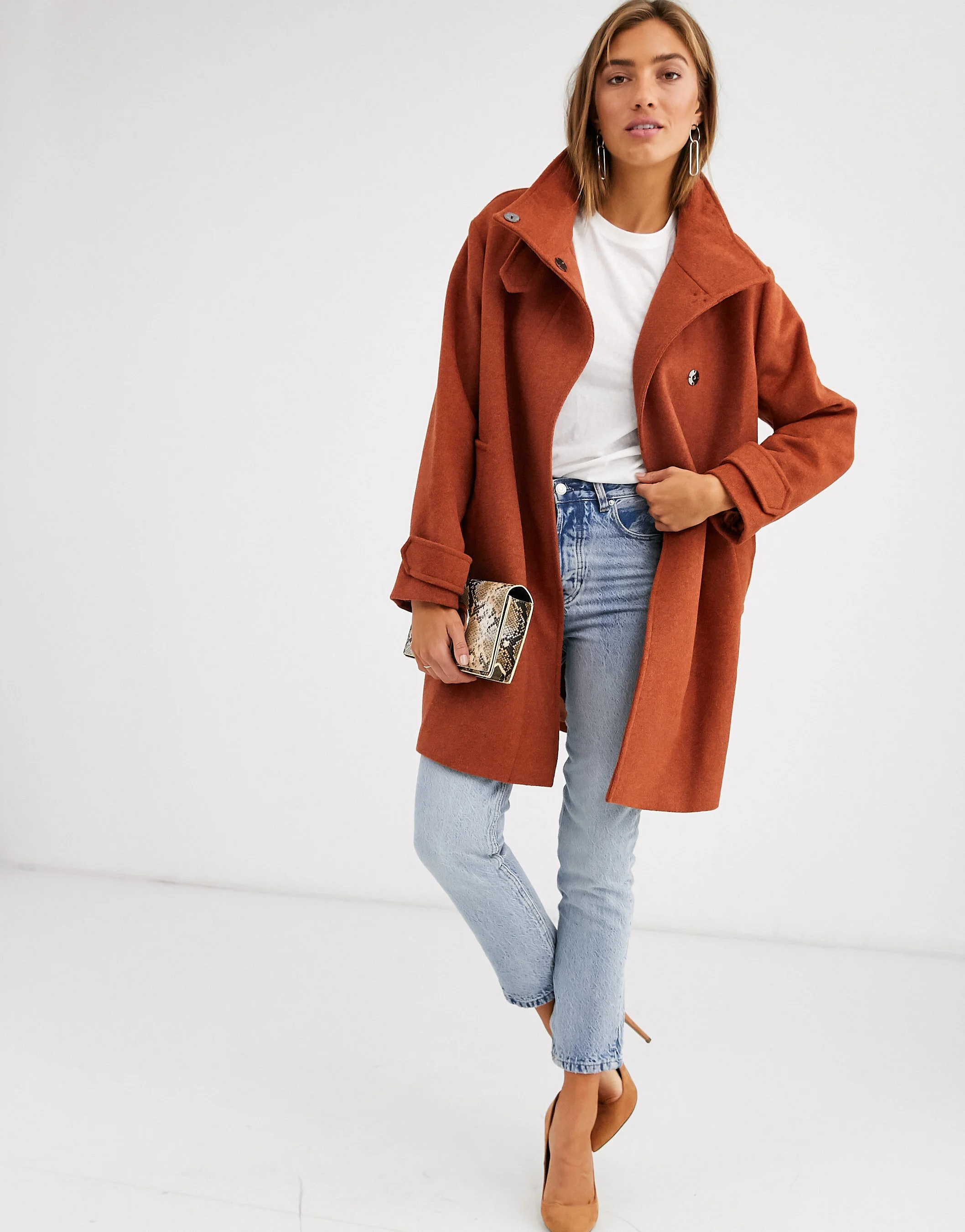 Female model in a white studio wearing casual clothing with an orange coat for ASOS
