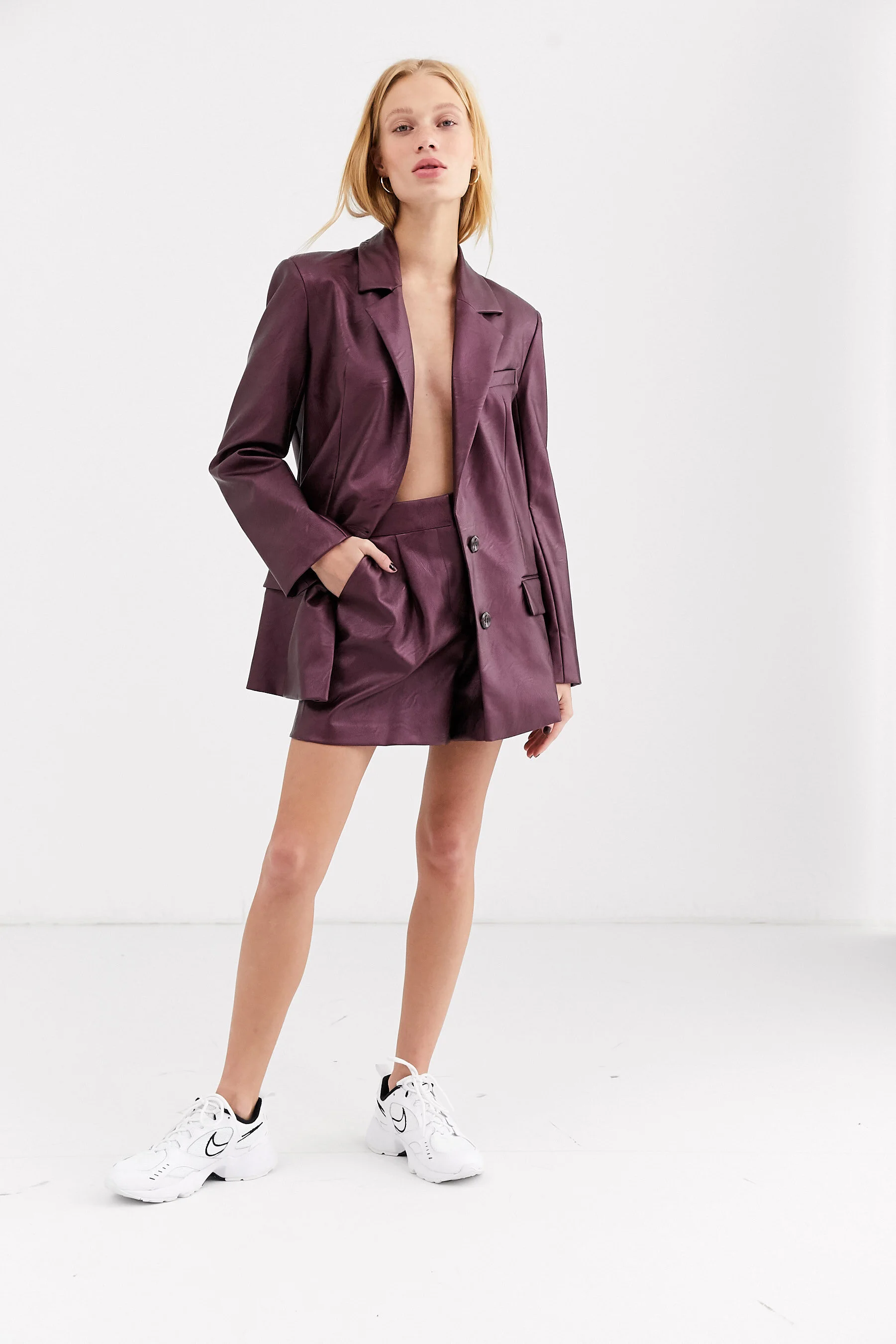 Blonde female model in a white studio wearing a purple jacket for ASOS