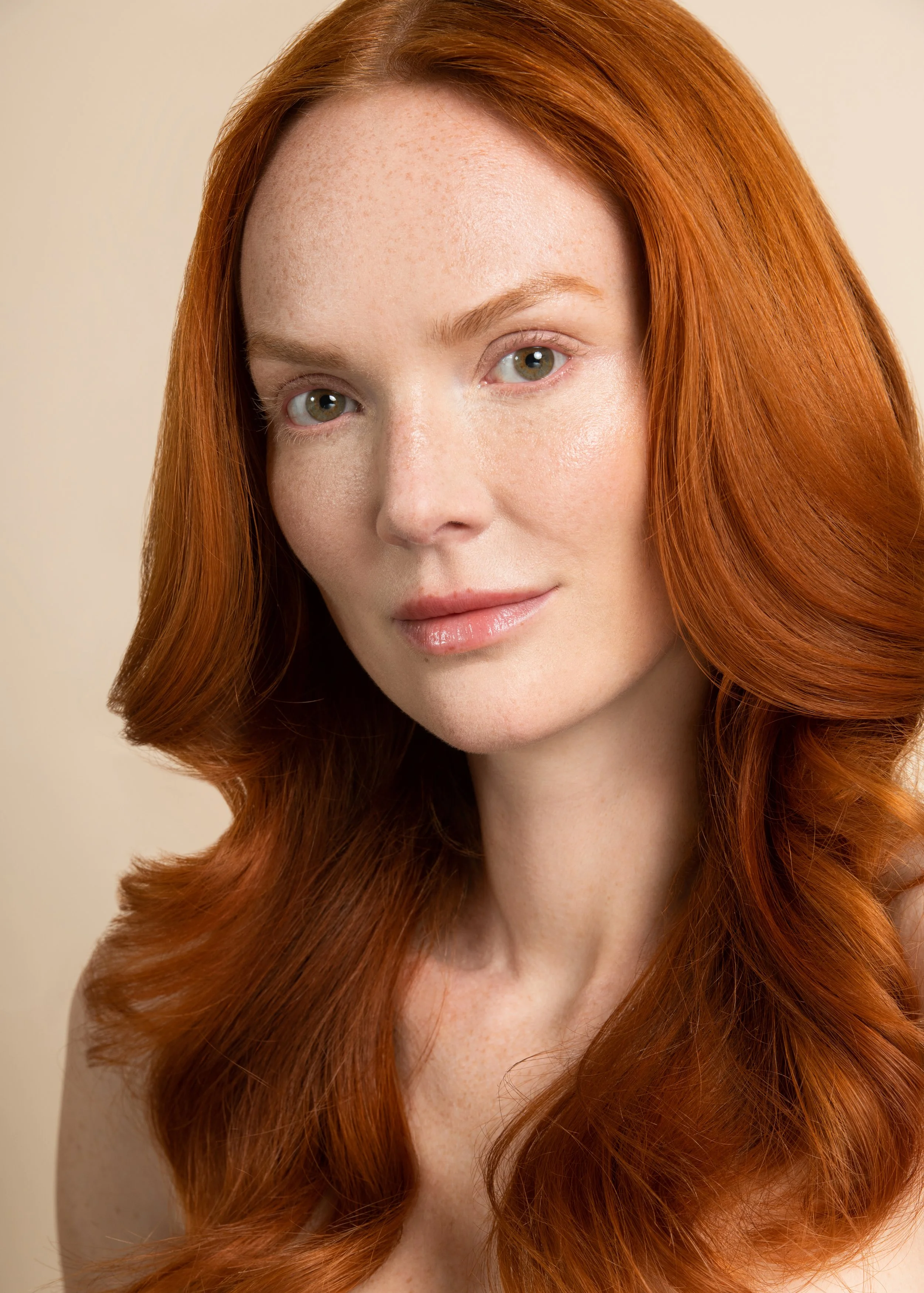 ginger beauty model with natural skin in front of beige photography background