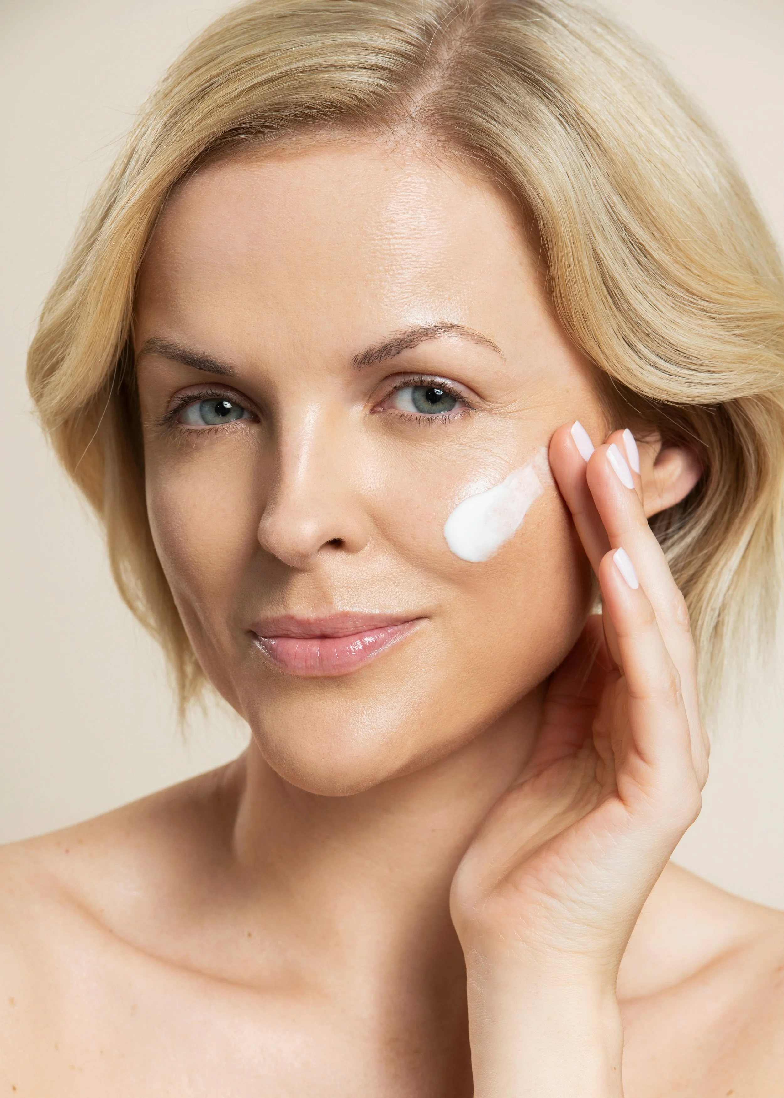 Blonde beauty model applying cream for Olivanna skincare photoshoot