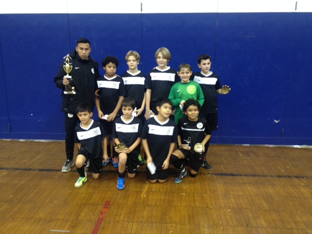 Met Oval players and coach showing off one of a host of trophies racked up this winter by Met Oval teams while working through a futsal winter training schedule.
