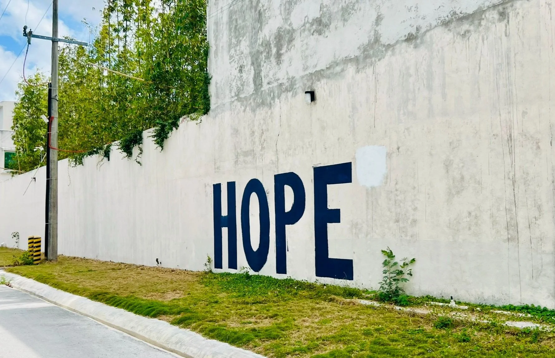 A white wall with the word "hope" painted in blue. This sign was outside of the ibogaine clinic where my healing journey began.