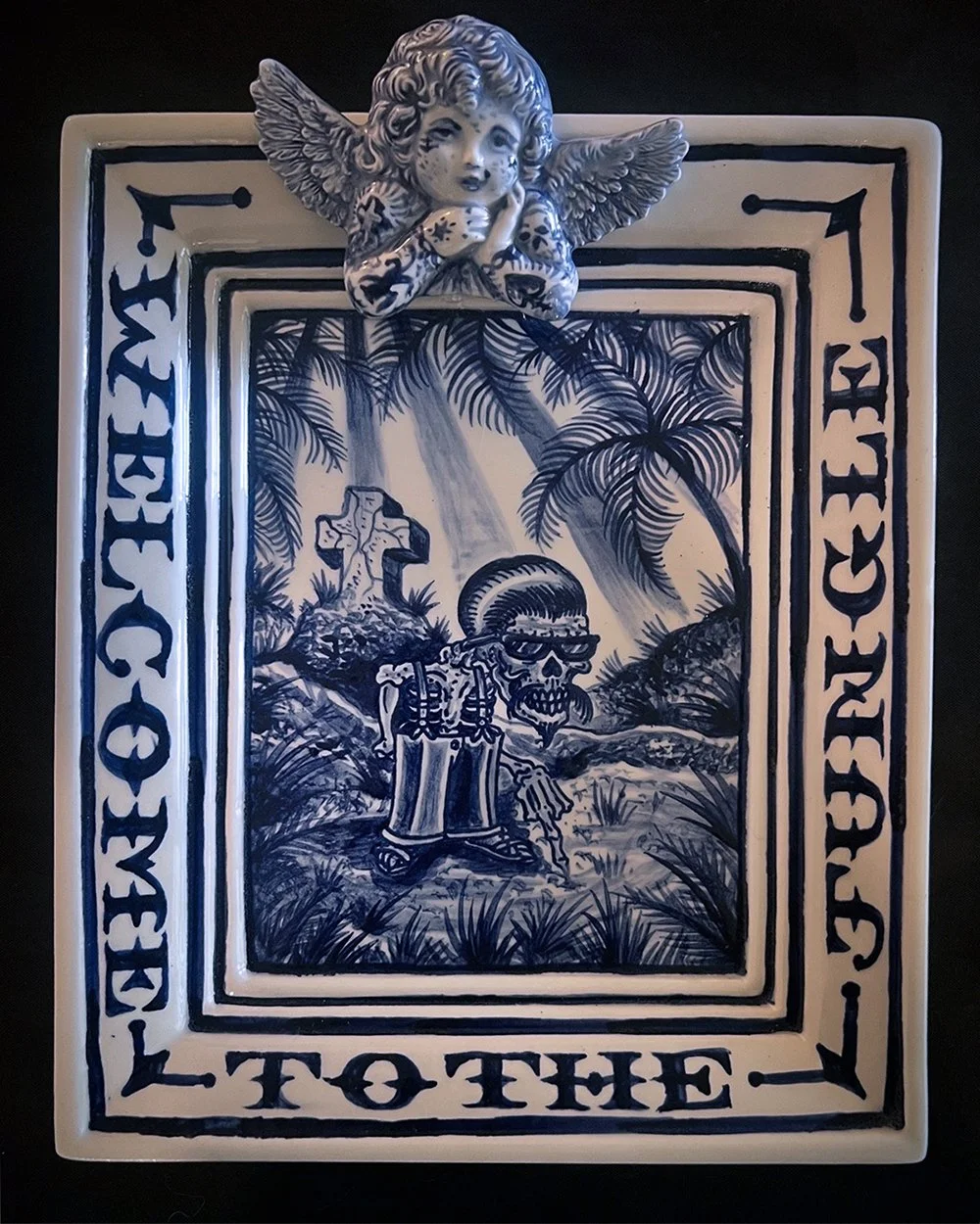 Ceramic plate by Britton McFetridge with cobalt glaze depicting a skeleton cholo with the phrase Welcome to the Jungle