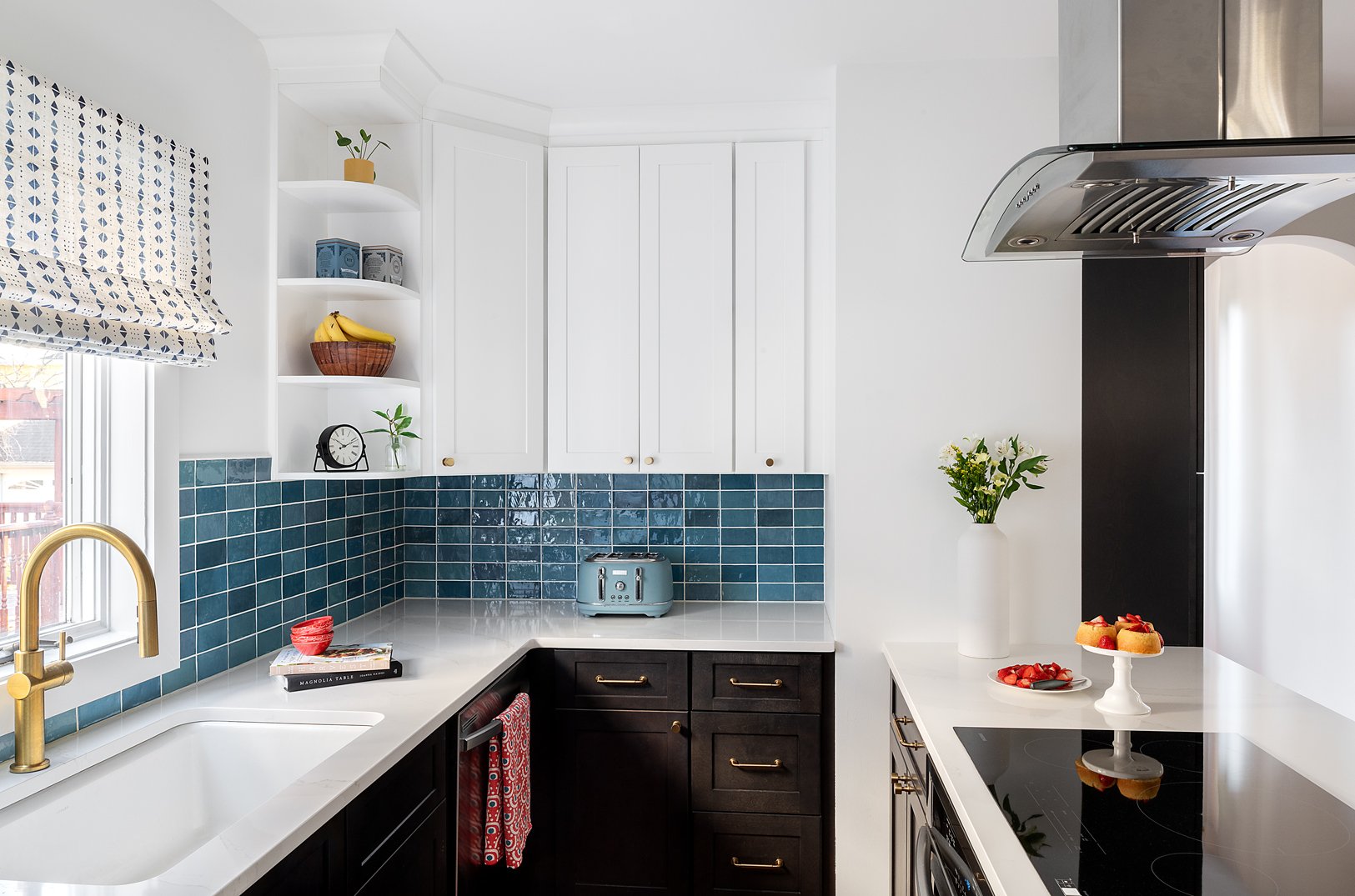 Kitchen with dark wood base cabinets and white upper cabinetry. Blue high variation backsplash tile.