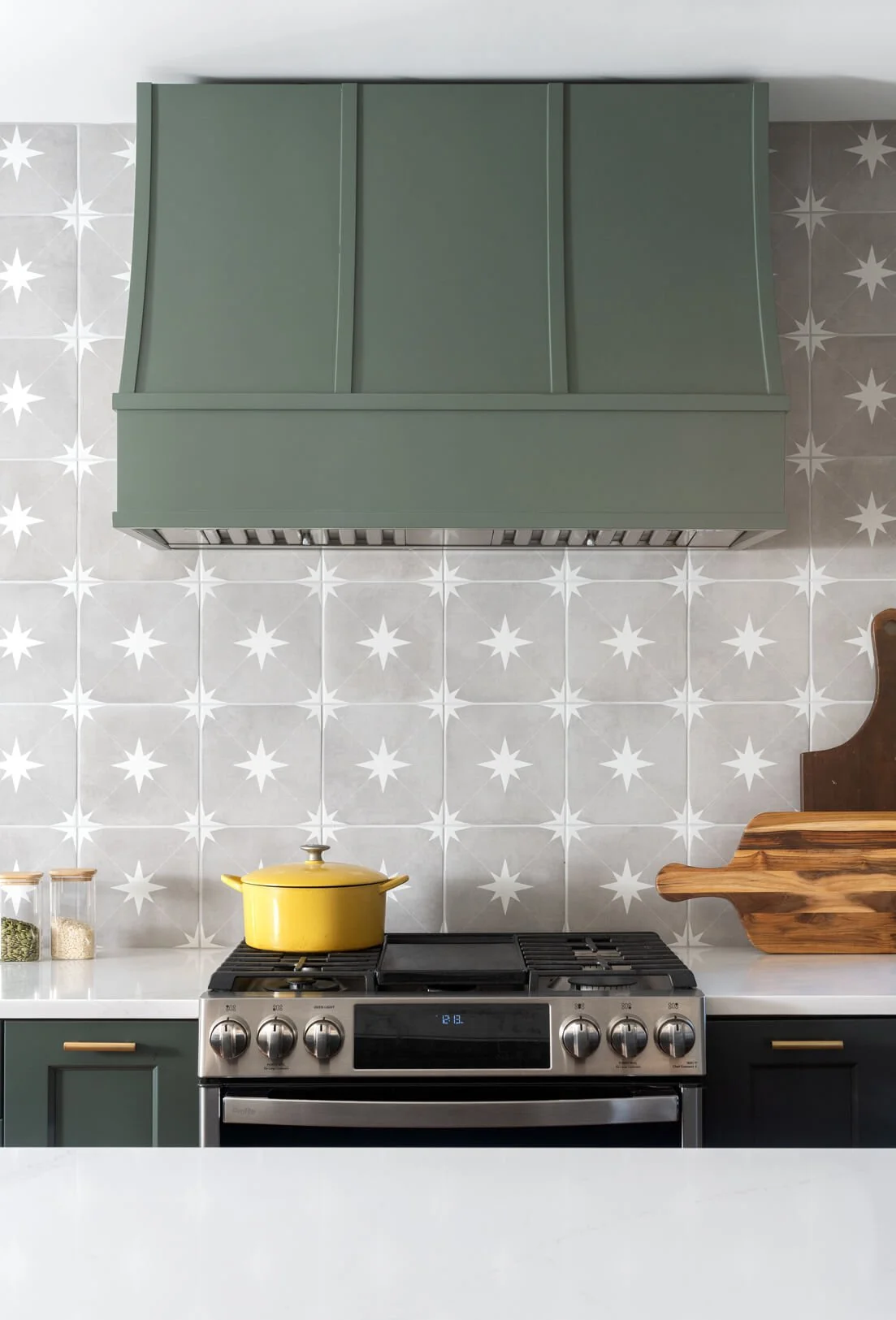 Range with dark green range hood and star backsplash.