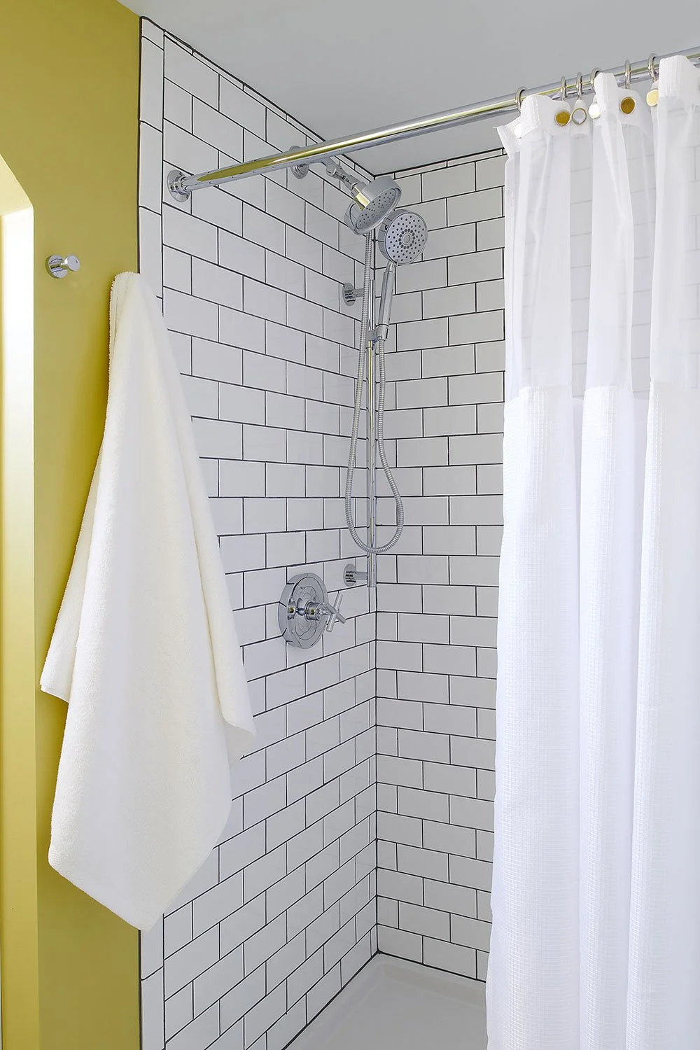 Shower with white subway tile and dark grout.