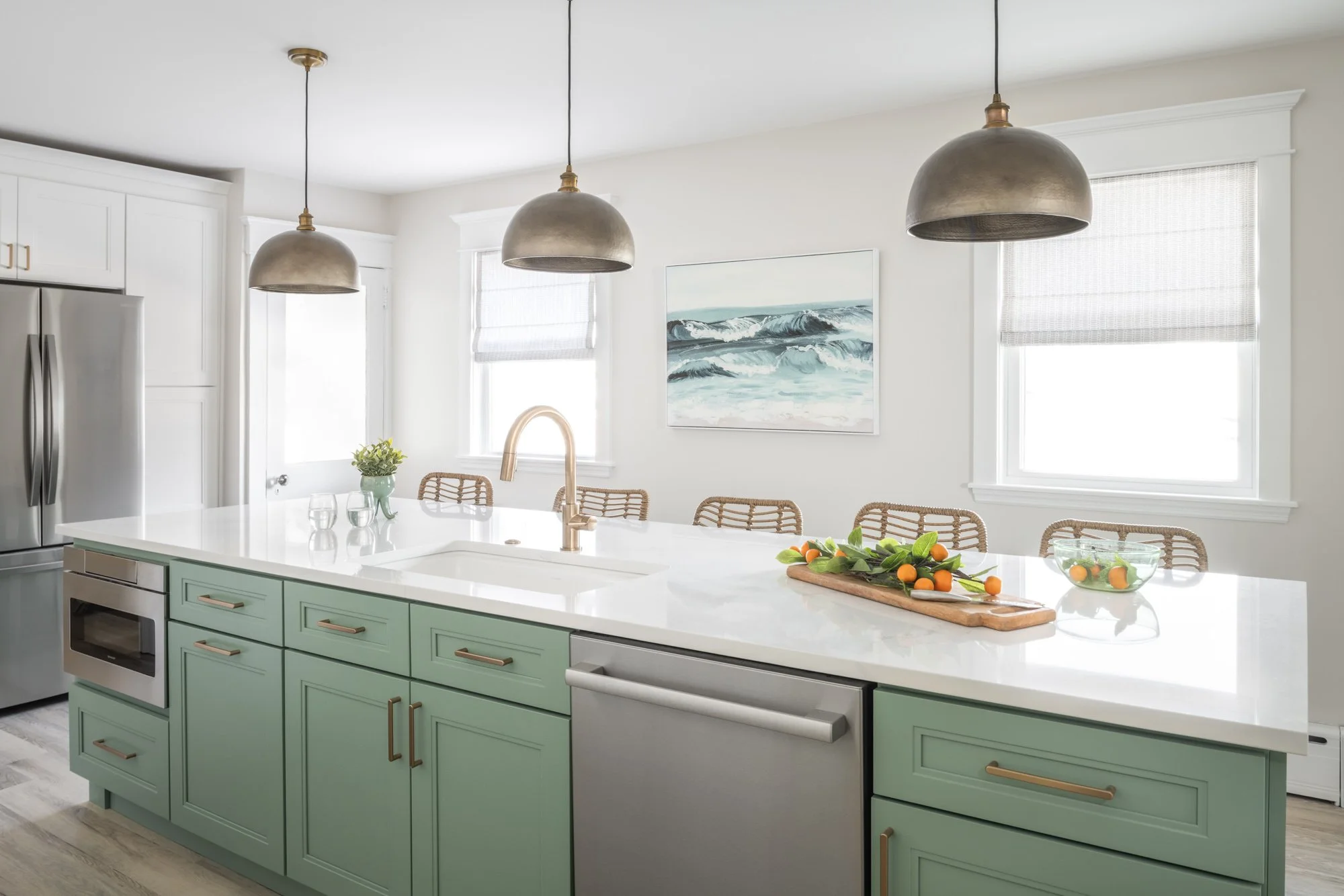 Large green kitchen island with windows and beach artwork in the background.