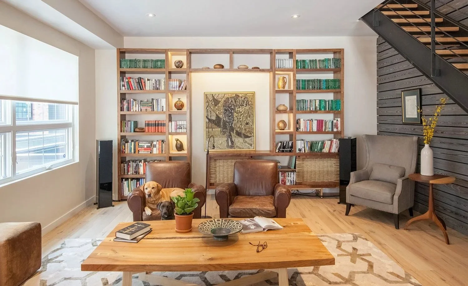 Living room with large wood bookshelf showcasing artwork and pottery.