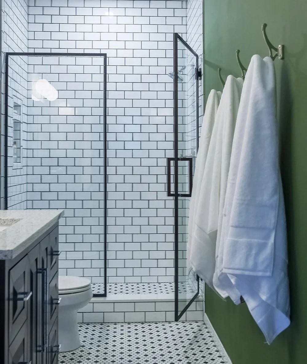 A modern, small apartment bathroom with a shower that has a glass enclosure.