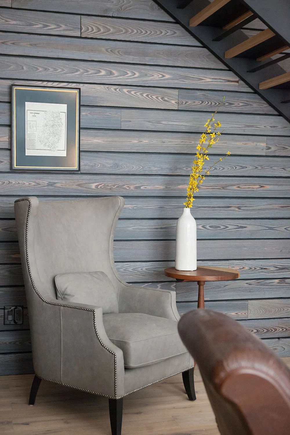 Gray high-back wing chair in front of accent wall.