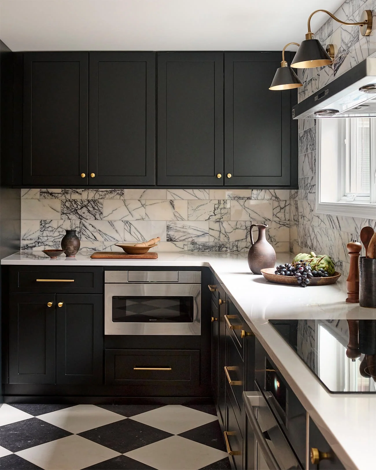Kitchen with black cabinetry, checkerboard tile floor and brass hardware.