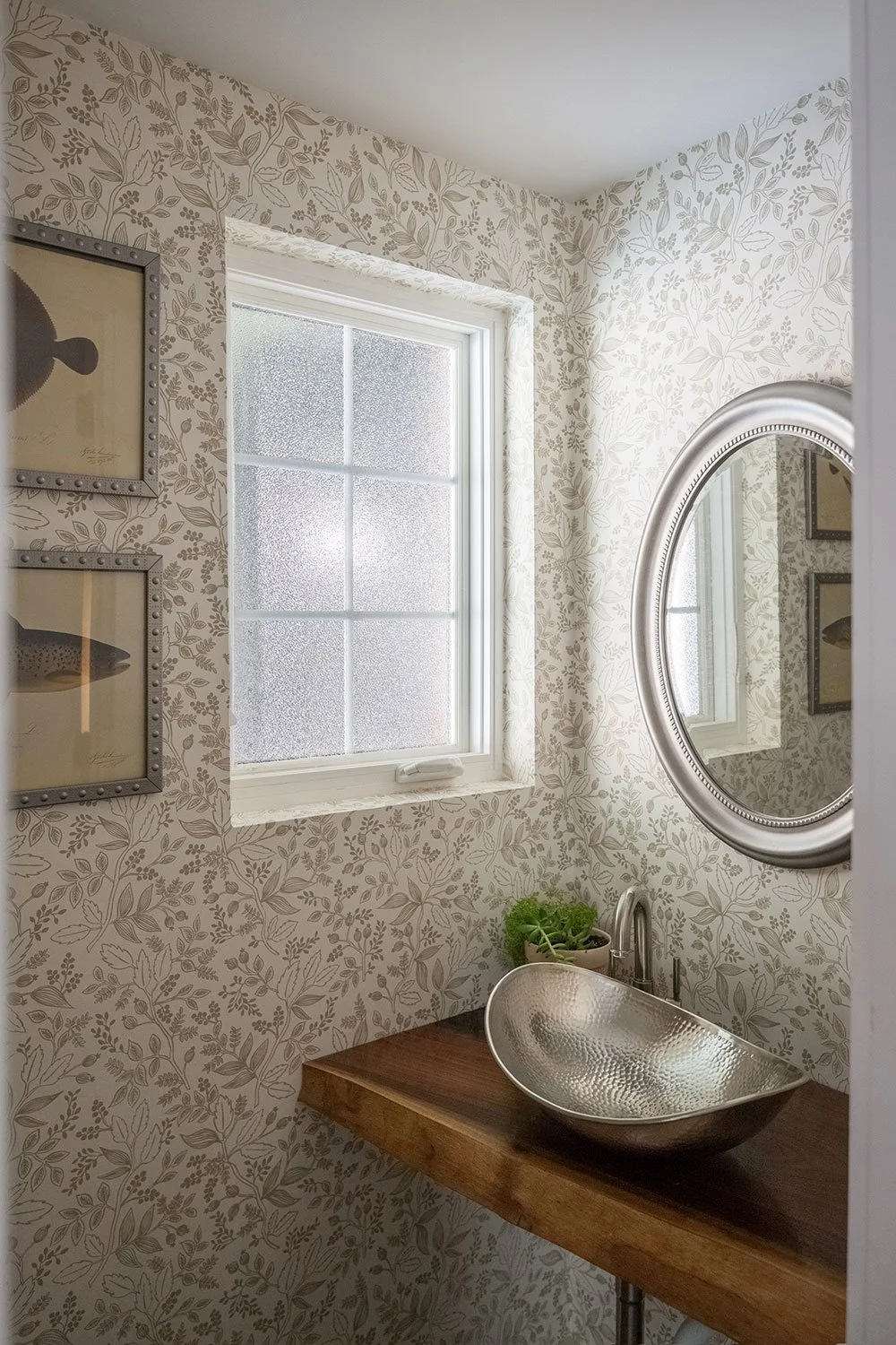 Powder room with neutral floral wallpaper and vessel sink.