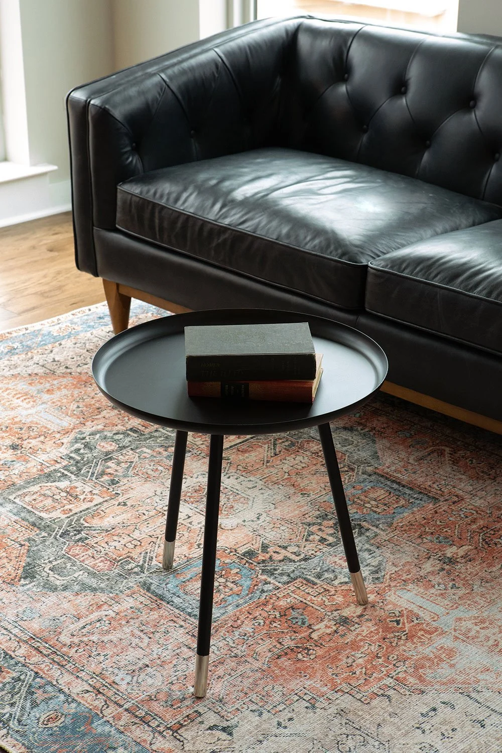 Oriental rug with black leather chesterfield sofa.