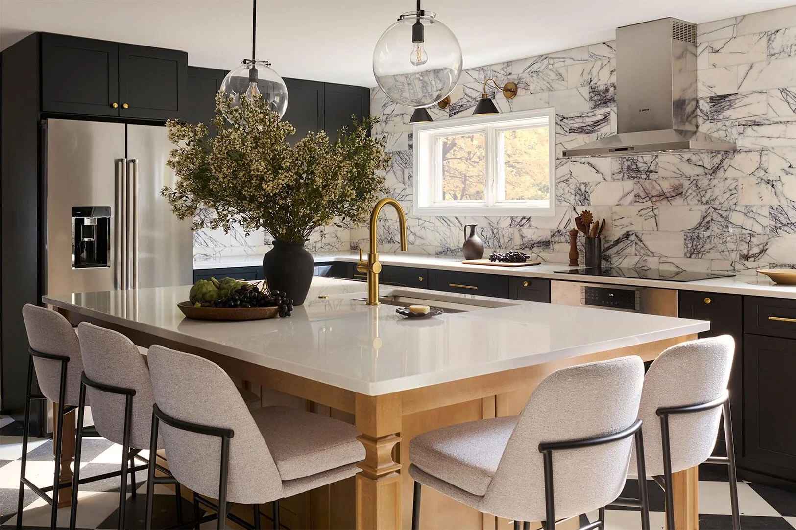 Kitchen with large wood island. Black perimeter cabinetry with violet marble backsplash.